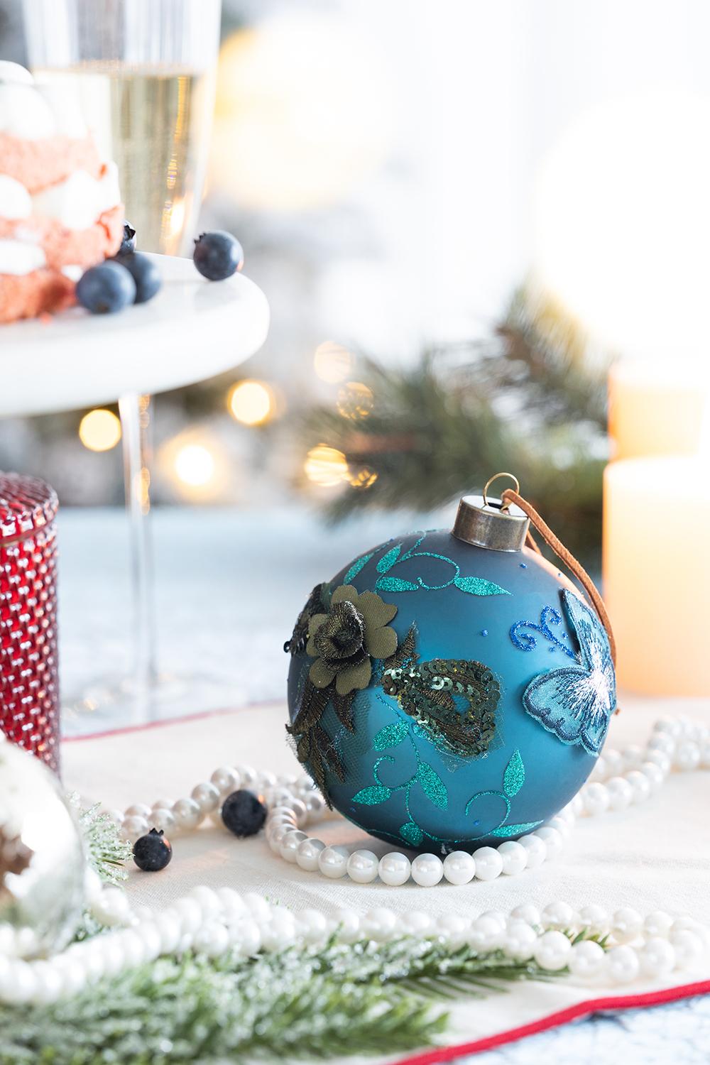 Teal glass Christmas ornament with embroidered flowers and butterflies ideal for holiday decor