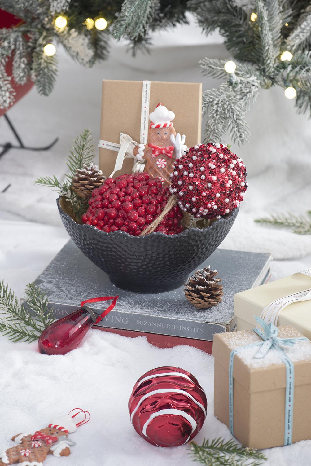 Textured black bowl filled with red berry clusters and festive ornaments