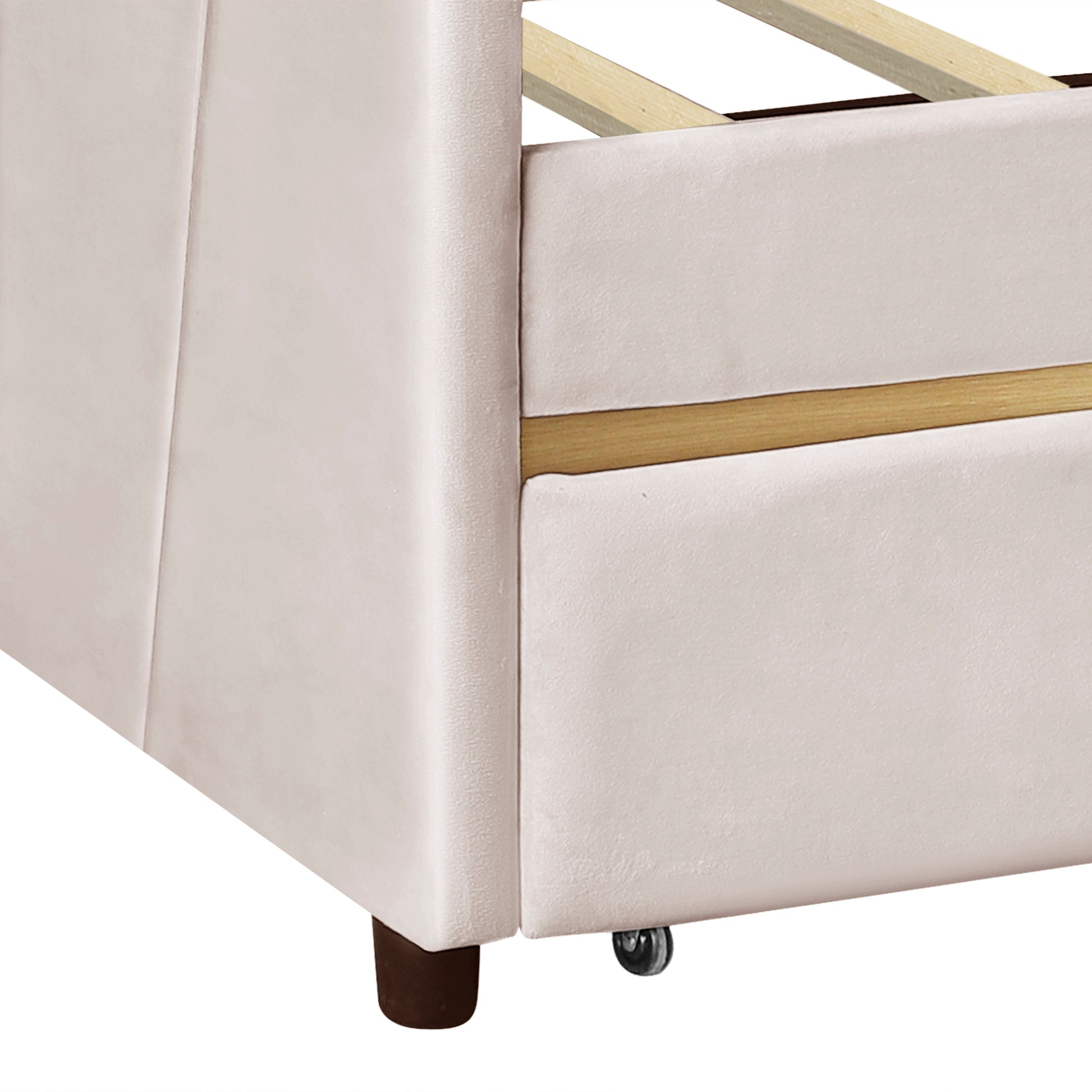 Closeup of plush beige velvet bed frame with wooden slats and caster wheel