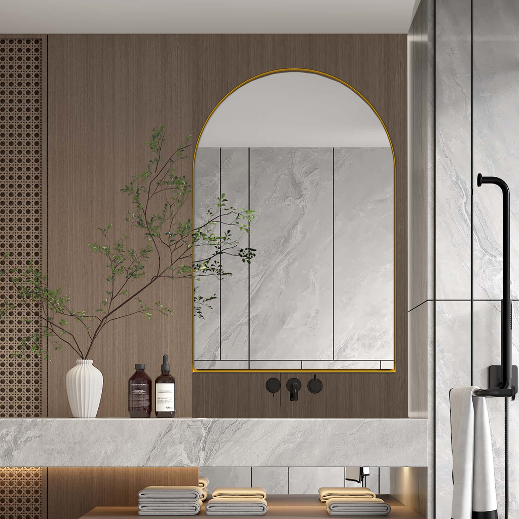 Arched gold framed bathroom mirror with marble backsplash and wood paneling