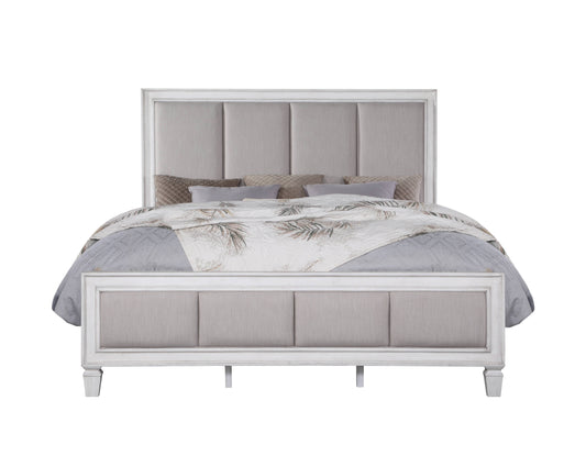 White upholstered queen bed with gray patterned bedding and decorative pillows