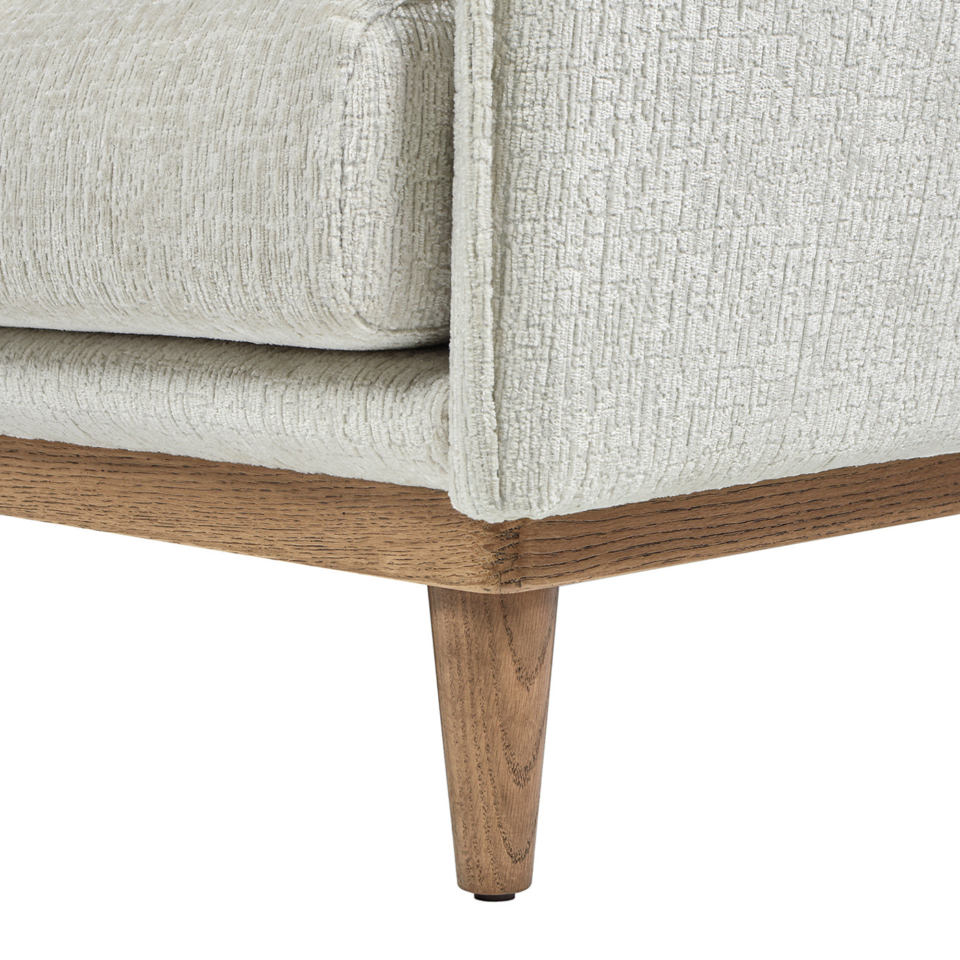 Closeup of a textured cream fabric sofa with a light oak wood base and tapered legs