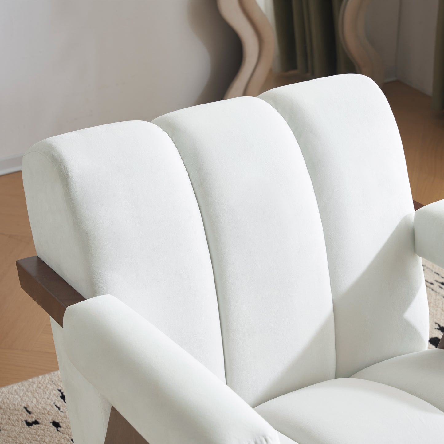 Plush white velvet armchair with dark wood armrest accents and deep channel tufting