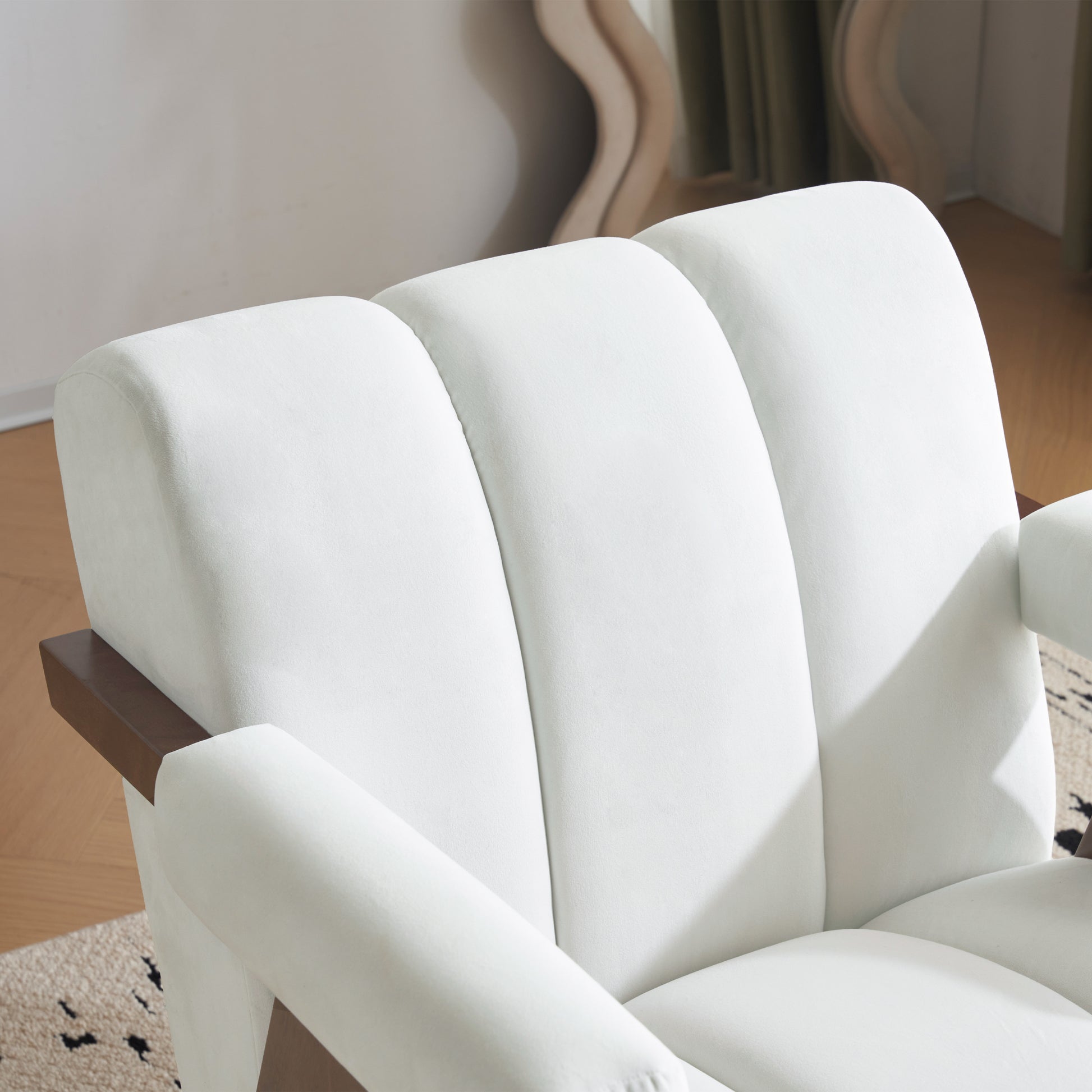 Plush white velvet armchair with dark wood armrest accents and deep channel tufting