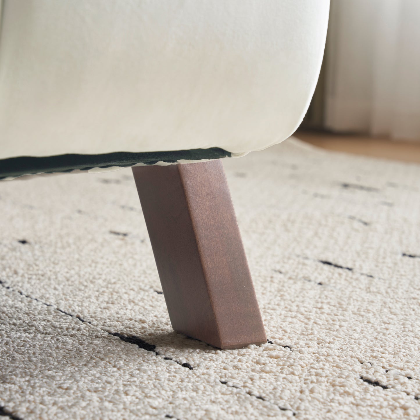 Closeup of a tapered dark wood furniture leg on a cream rug