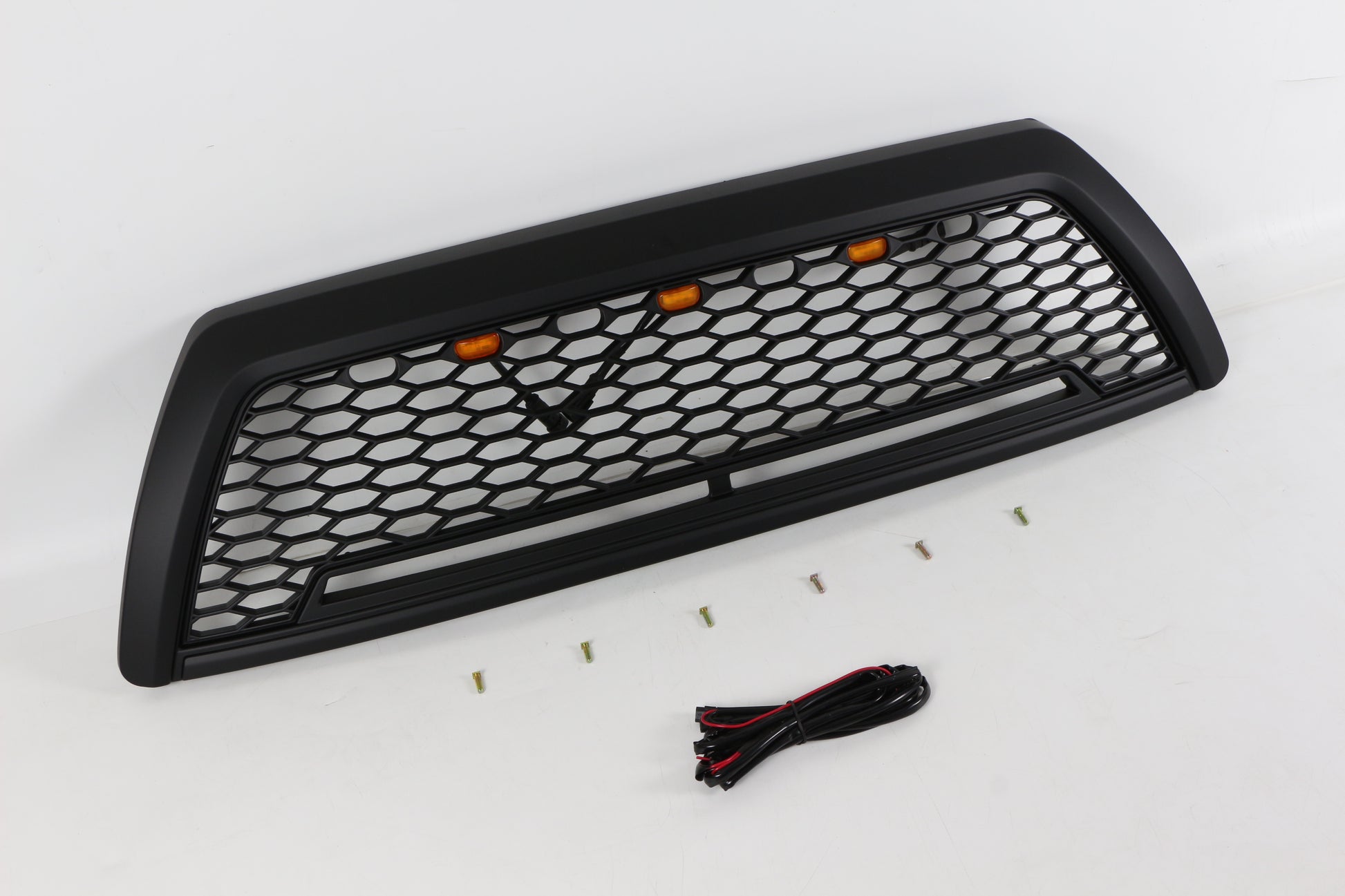 Black honeycomb truck grille with amber accent lights and mounting hardware