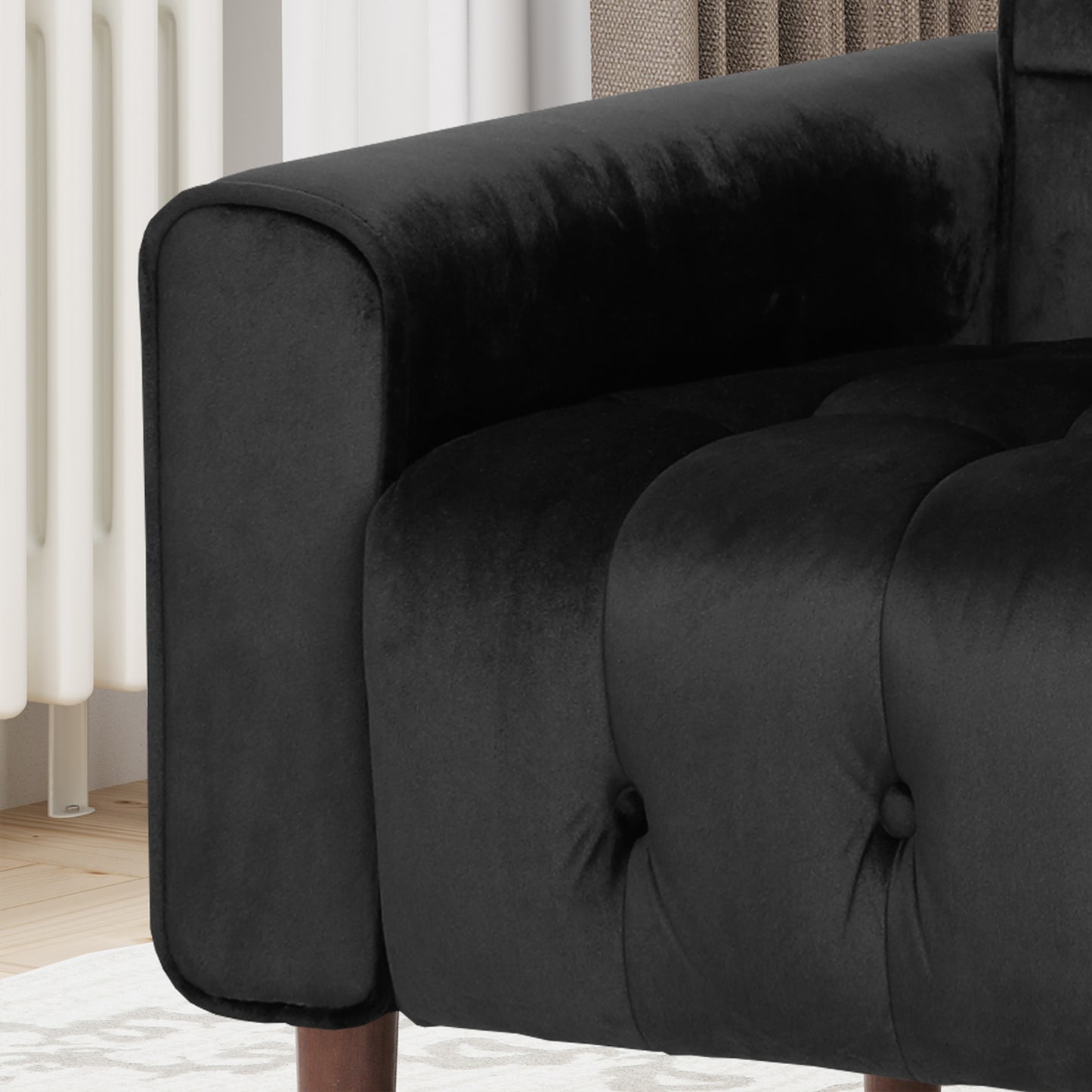 Closeup of tufted black velvet armchair with a rounded armrest