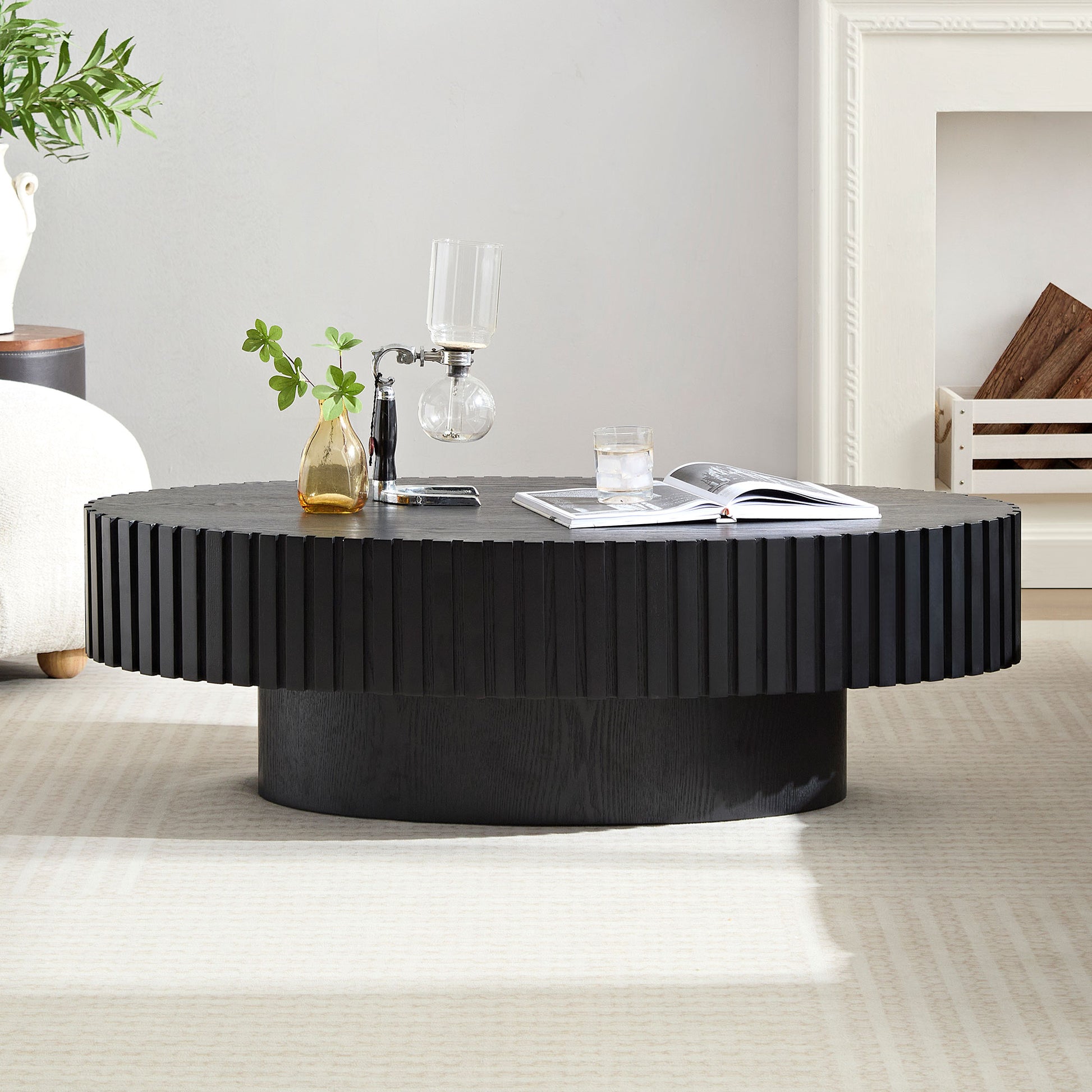Fluted black wood coffee table with a modern pedestal base in a living room setting