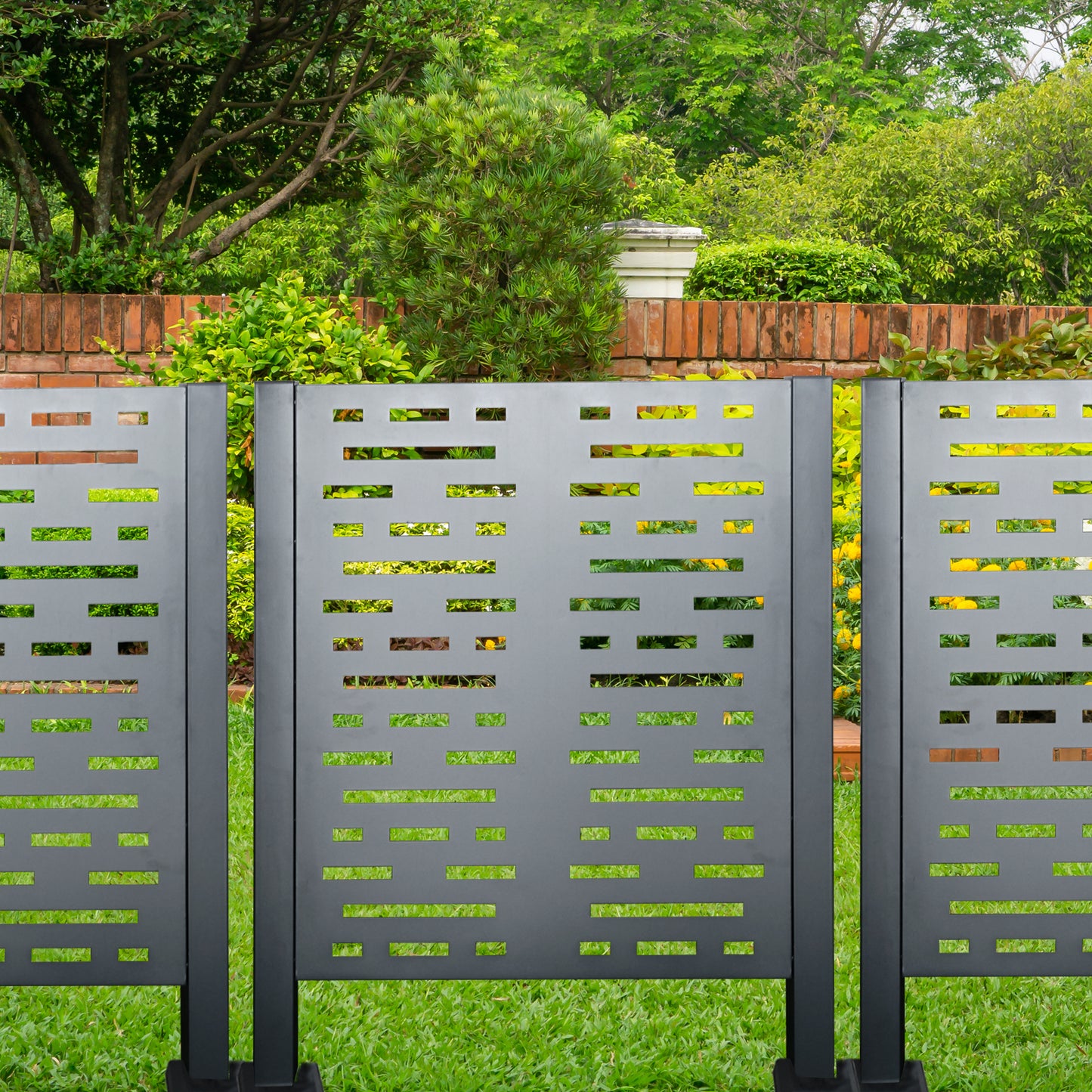 Modern dark gray metal garden screen with geometric cutouts providing privacy and style