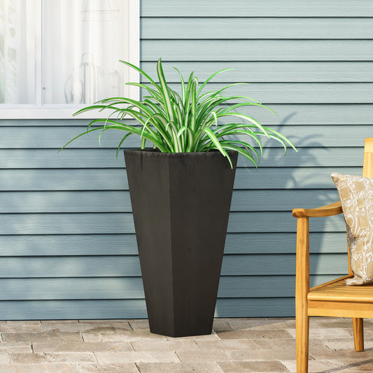 Tall black planter with a spider plant on a patio next to a wooden chair