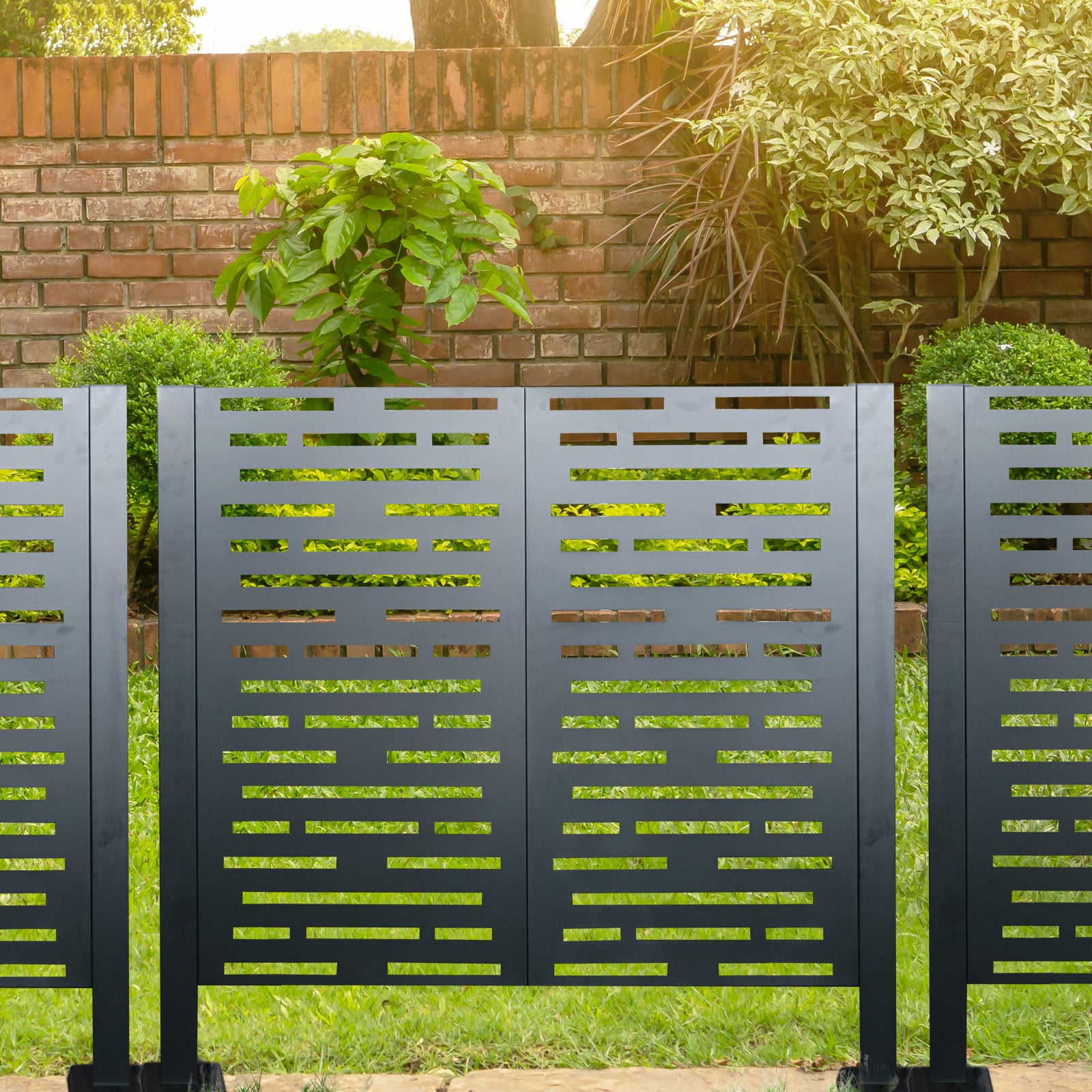 Modern charcoal metal fence panels with decorative cutouts in a backyard setting