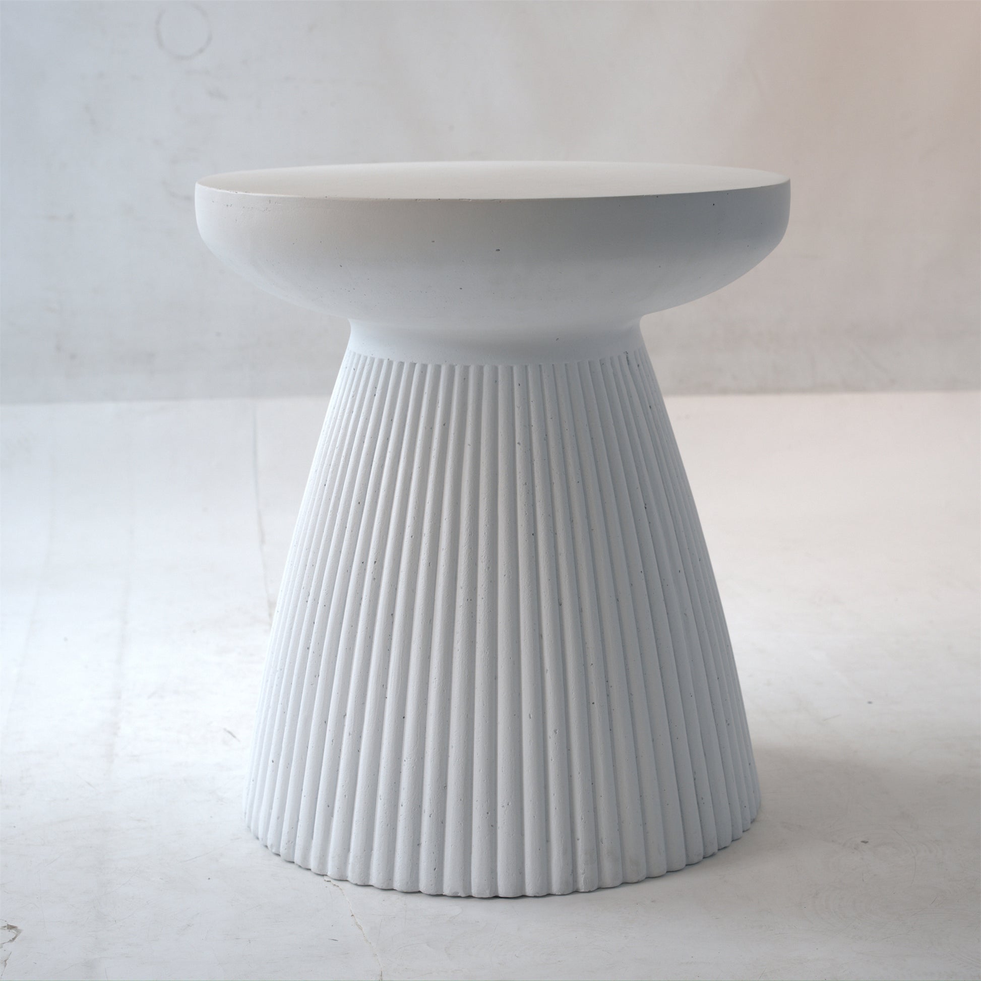 White fluted concrete stool with a rounded top and tapered base modern accent table