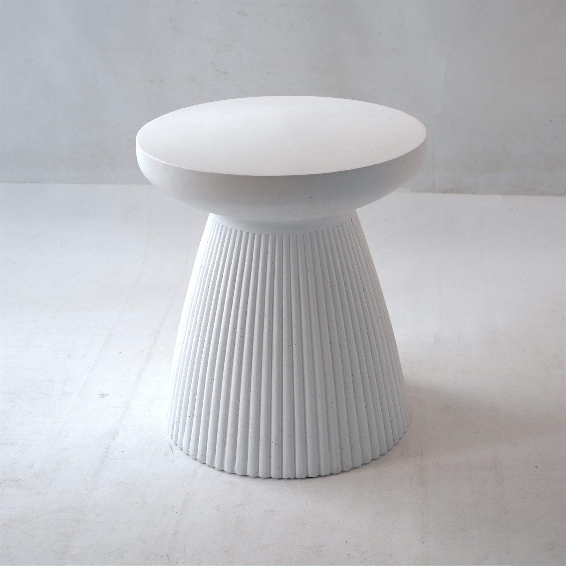 White fluted concrete side table with a smooth rounded top A modern accent stool