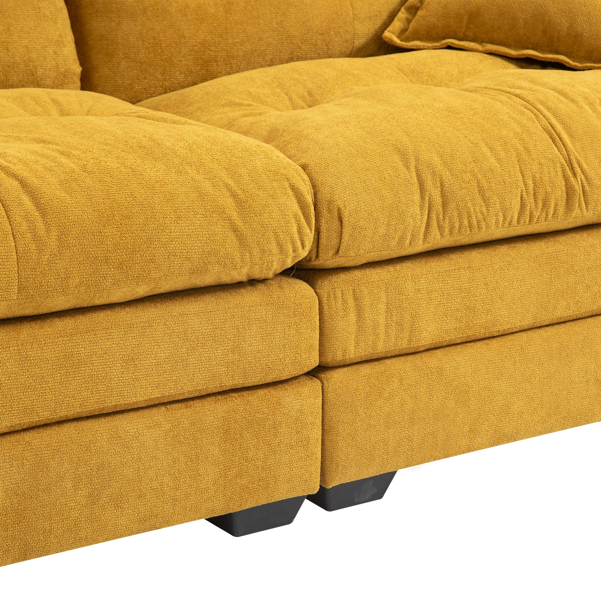 Closeup of a plush mustard yellow velvet sofas armrest and cushions