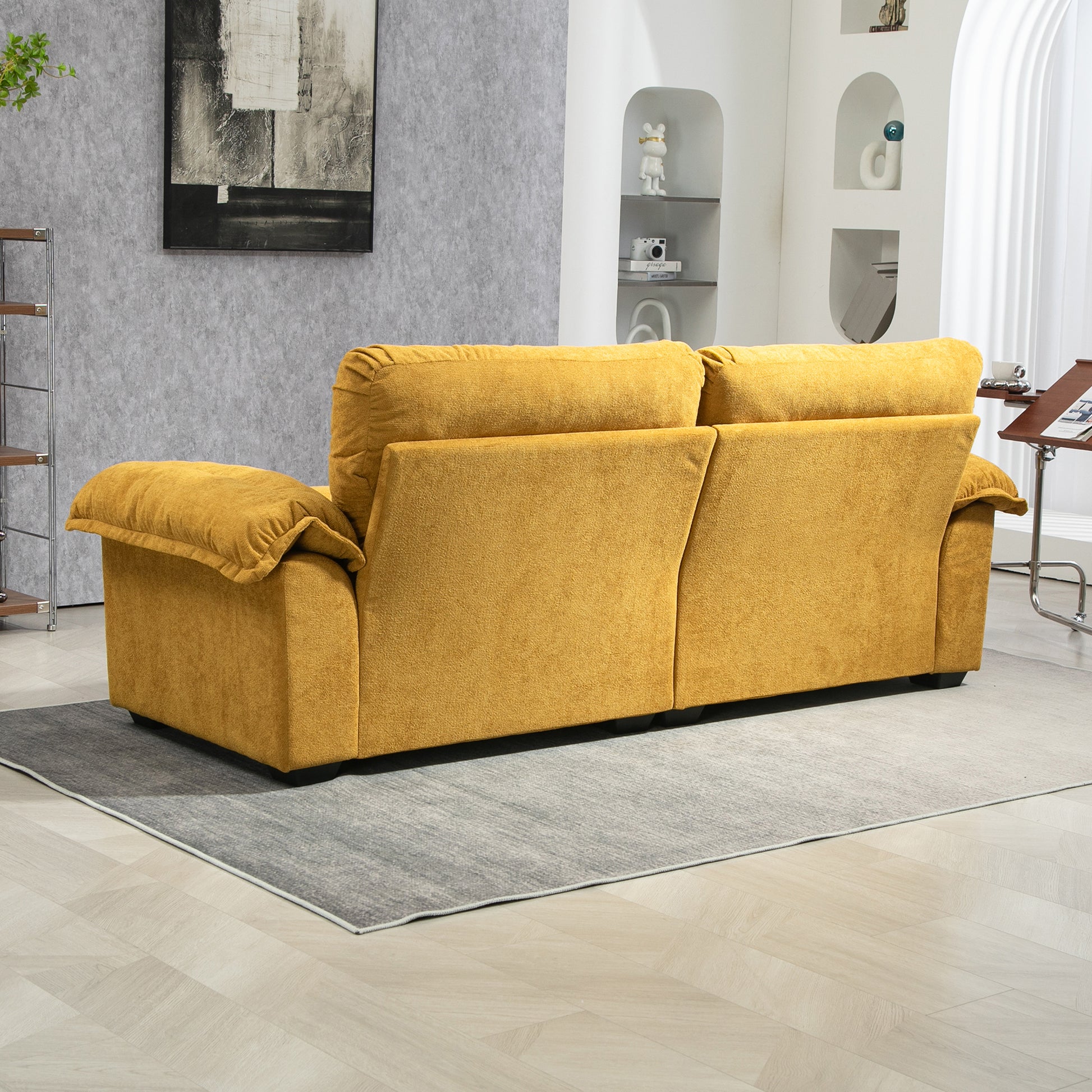 Plush mustard yellow velvet sofa with rolled armrests on a gray rug