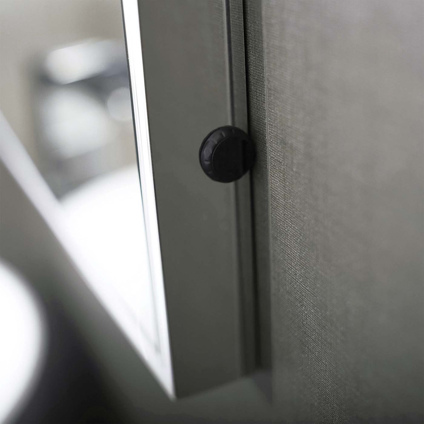 Closeup of a black textured cabinet knob on a gray fabriccovered door