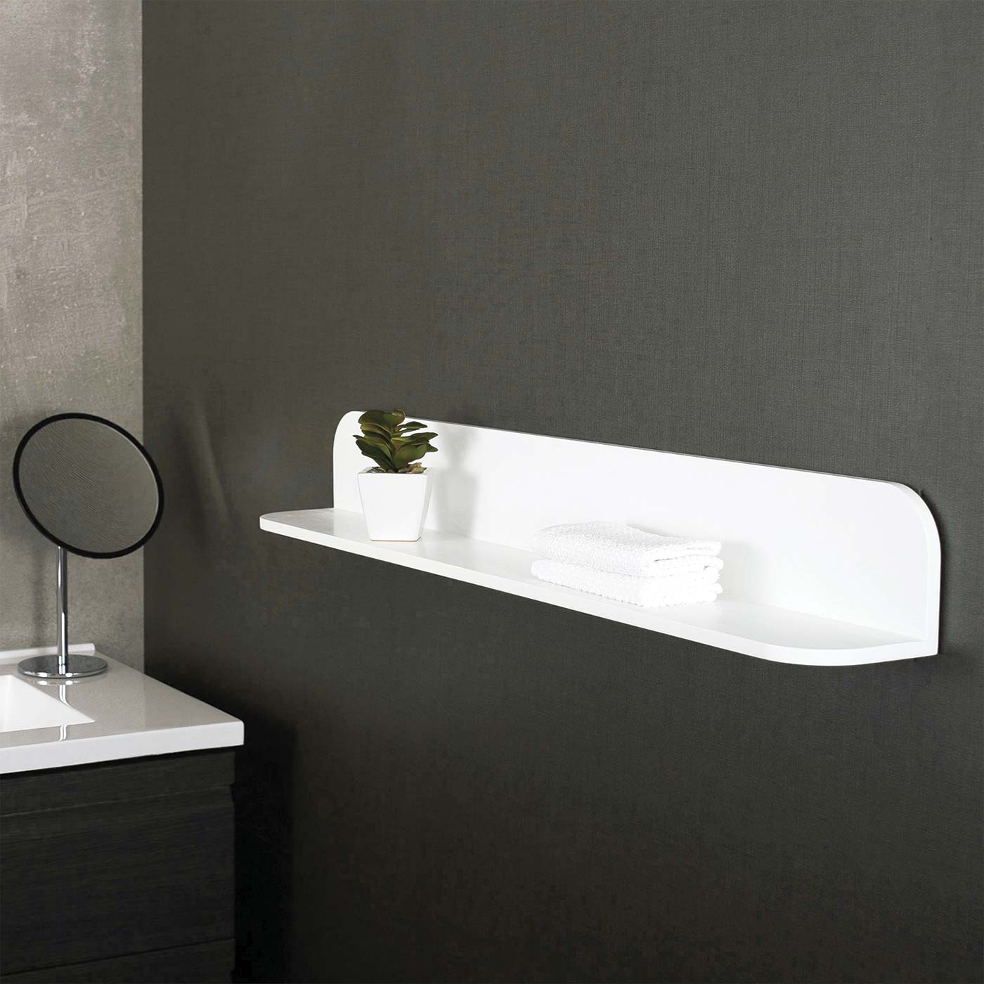 White floating shelf with rounded edges holding a small plant and folded towels