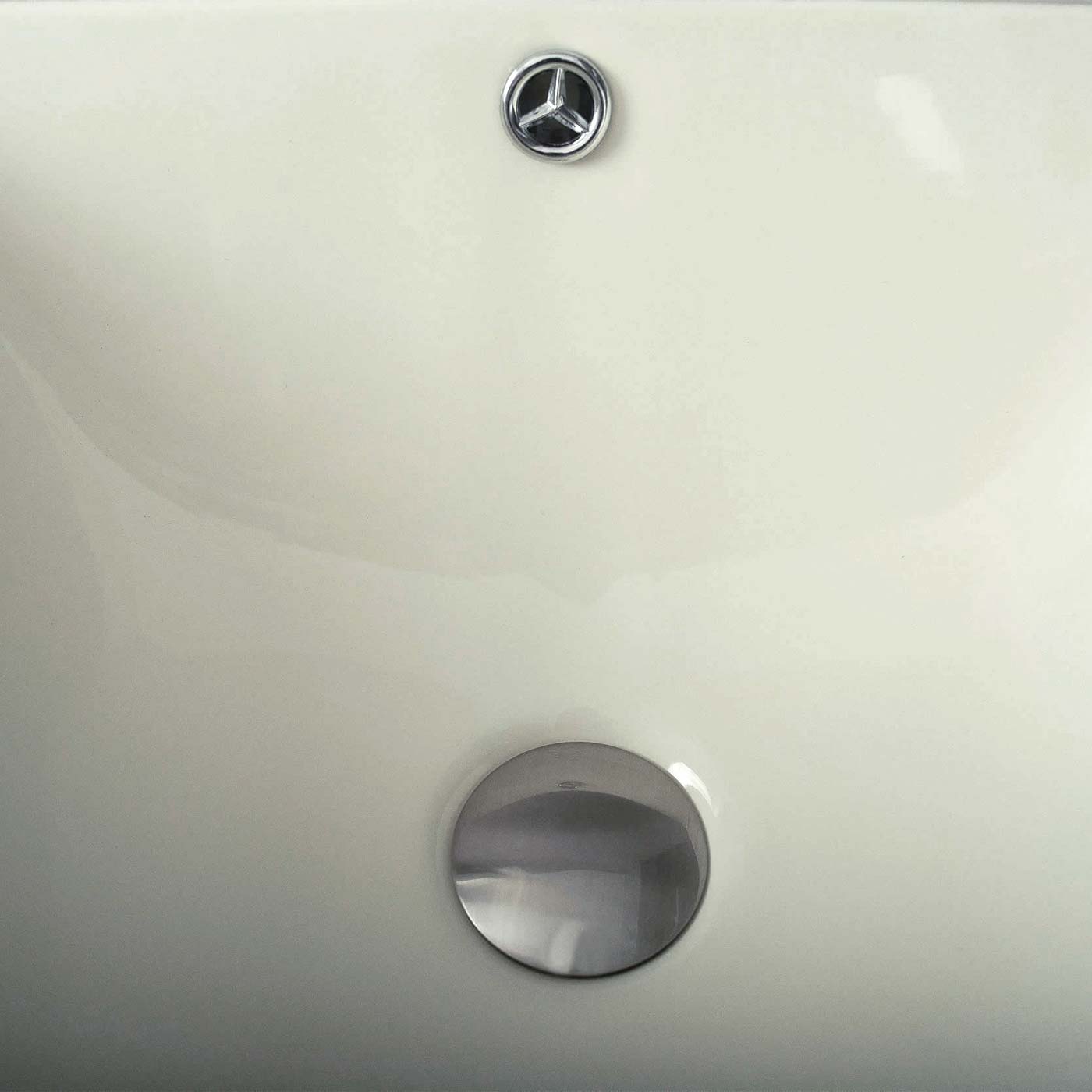 Cream colored toilet tank with chrome flush lever and lid emblem