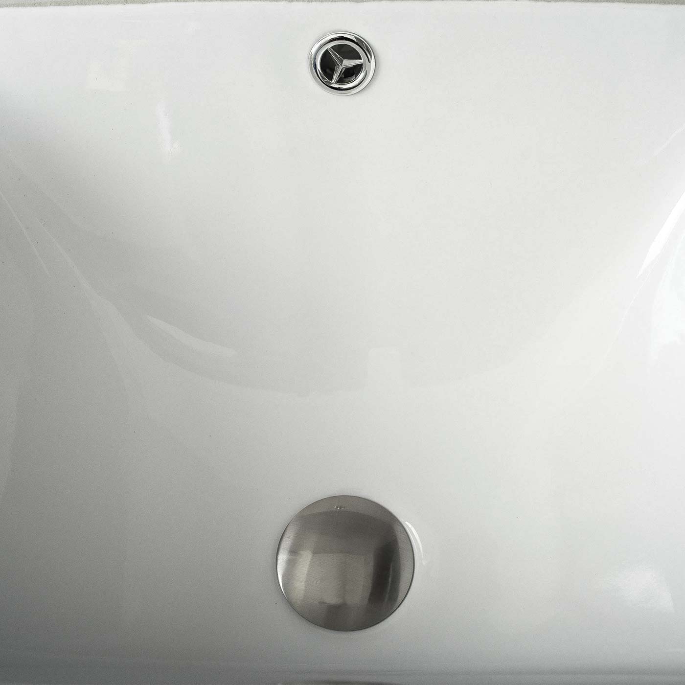 White ceramic bathroom sink interior with chrome drain and overflow cover