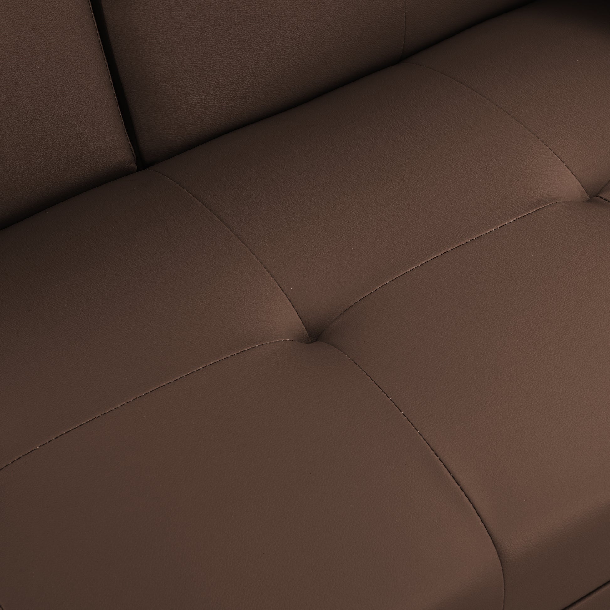 Closeup of tufted brown leather sofa cushion with detailed stitching adding modern elegance