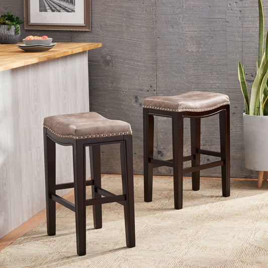 Two tufted brown leatherette bar stools with nailhead trim and dark wood legs