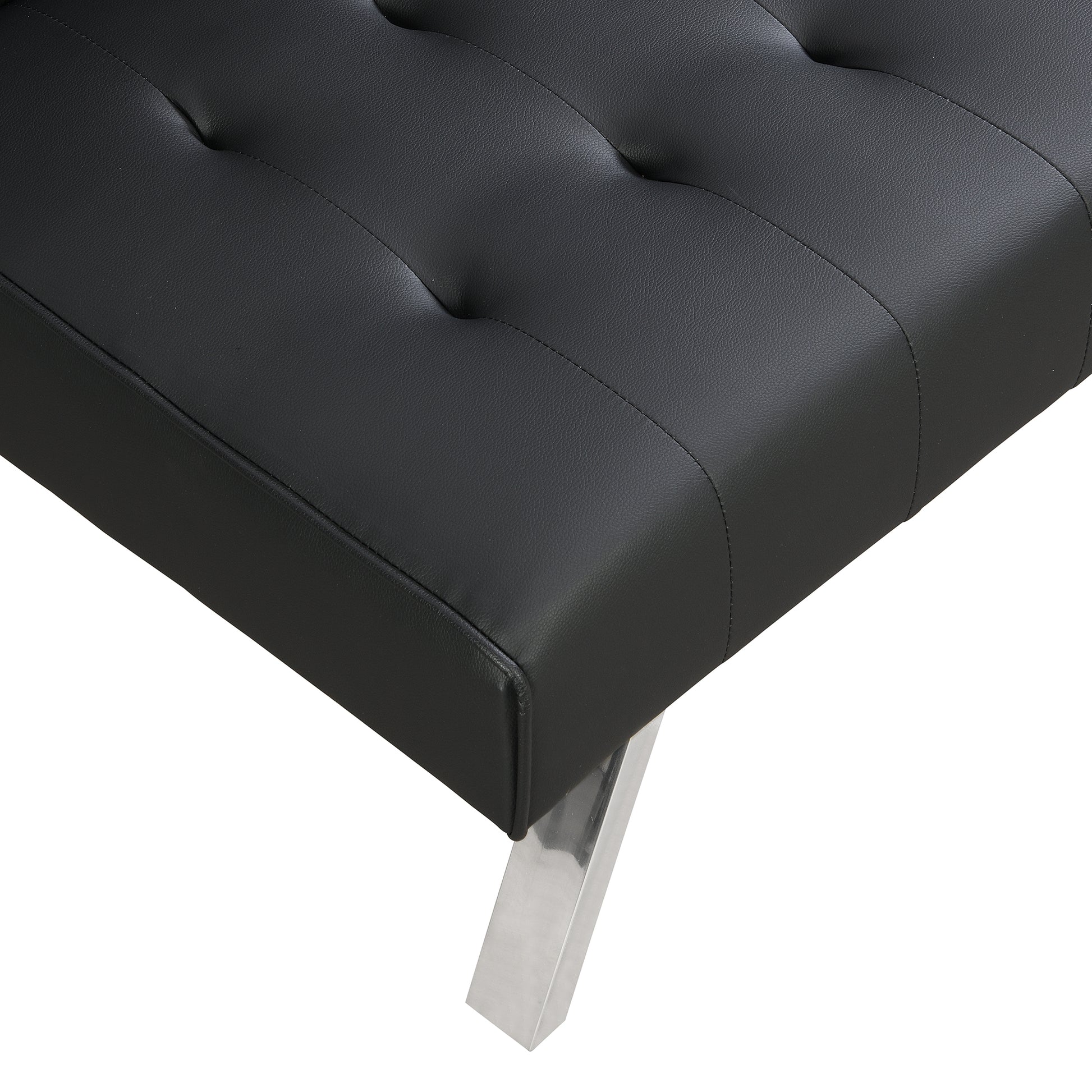 Closeup of tufted black faux leather sofa seat with silver metal leg detail