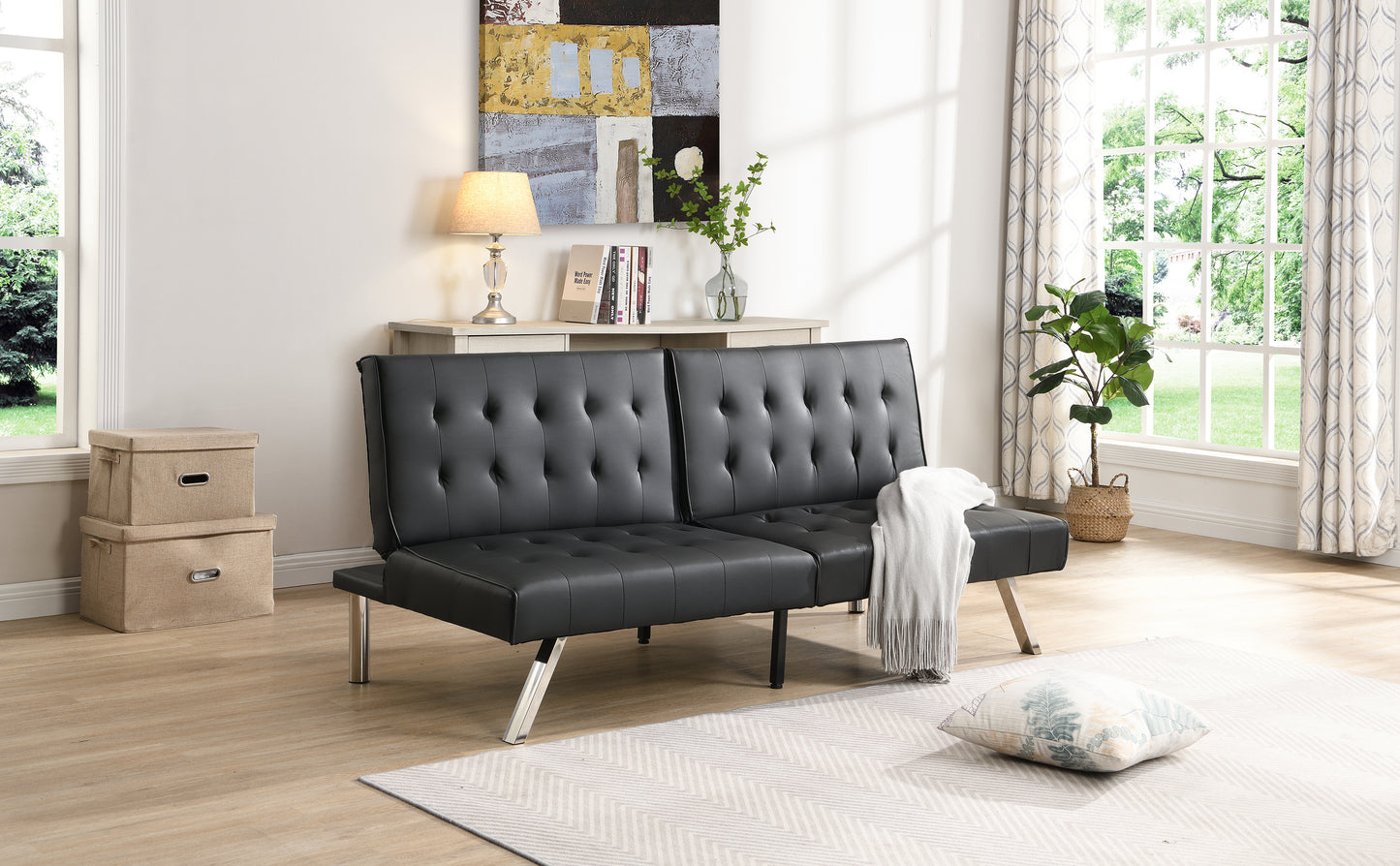 Tufted black faux leather futon sofa with chrome legs and a throw blanket
