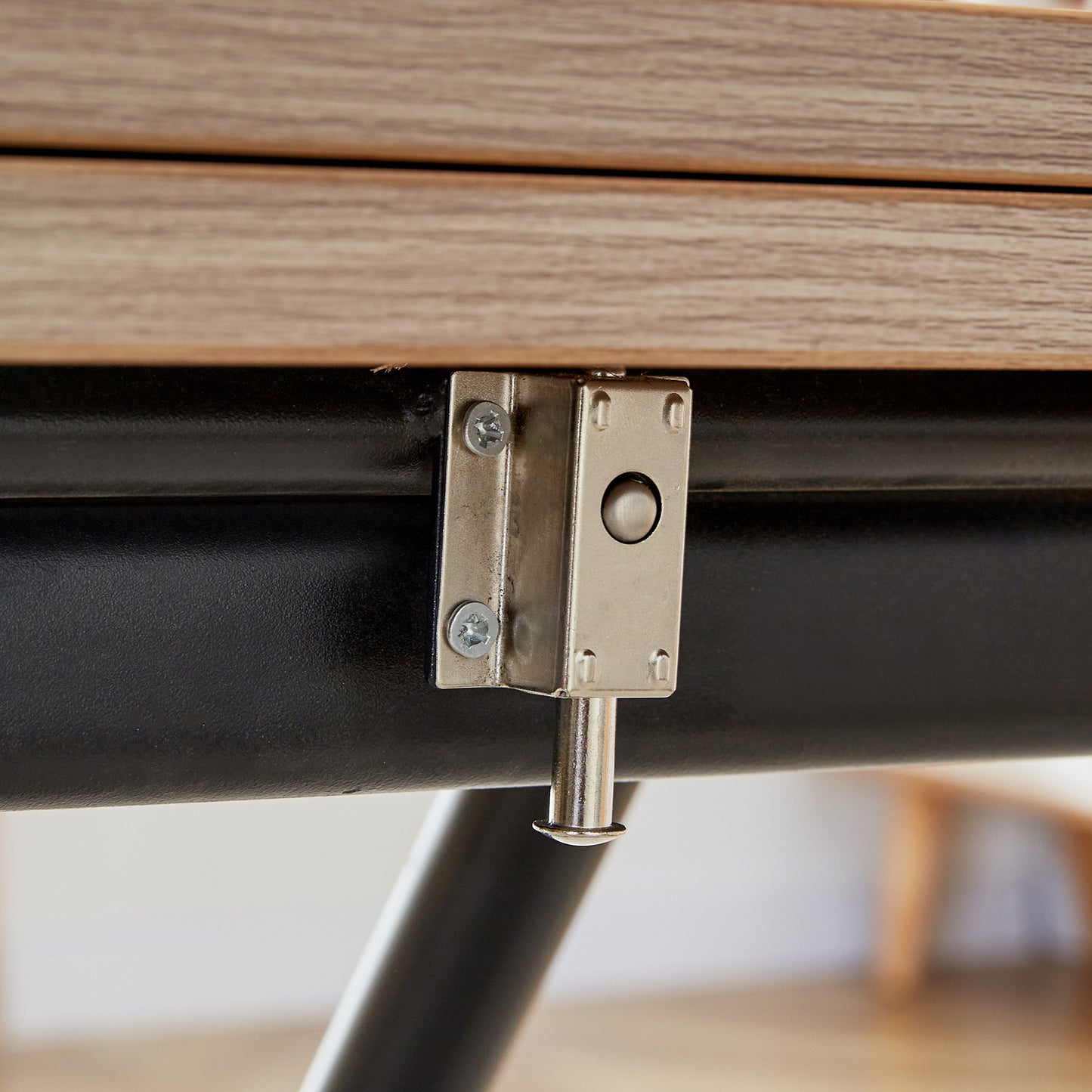 Table latch mechanism metal securing wooden tabletop to black frame for stability