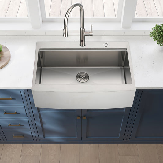 Farmhouse stainless steel kitchen sink with a brushed nickel faucet and drain