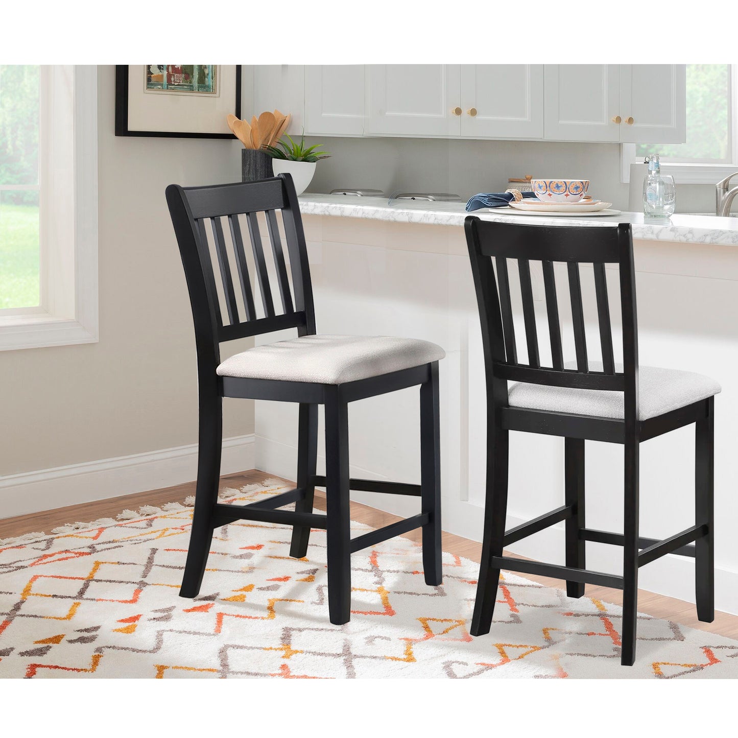 Two black wooden bar stools with light grey upholstered seats in a modern kitchen setting