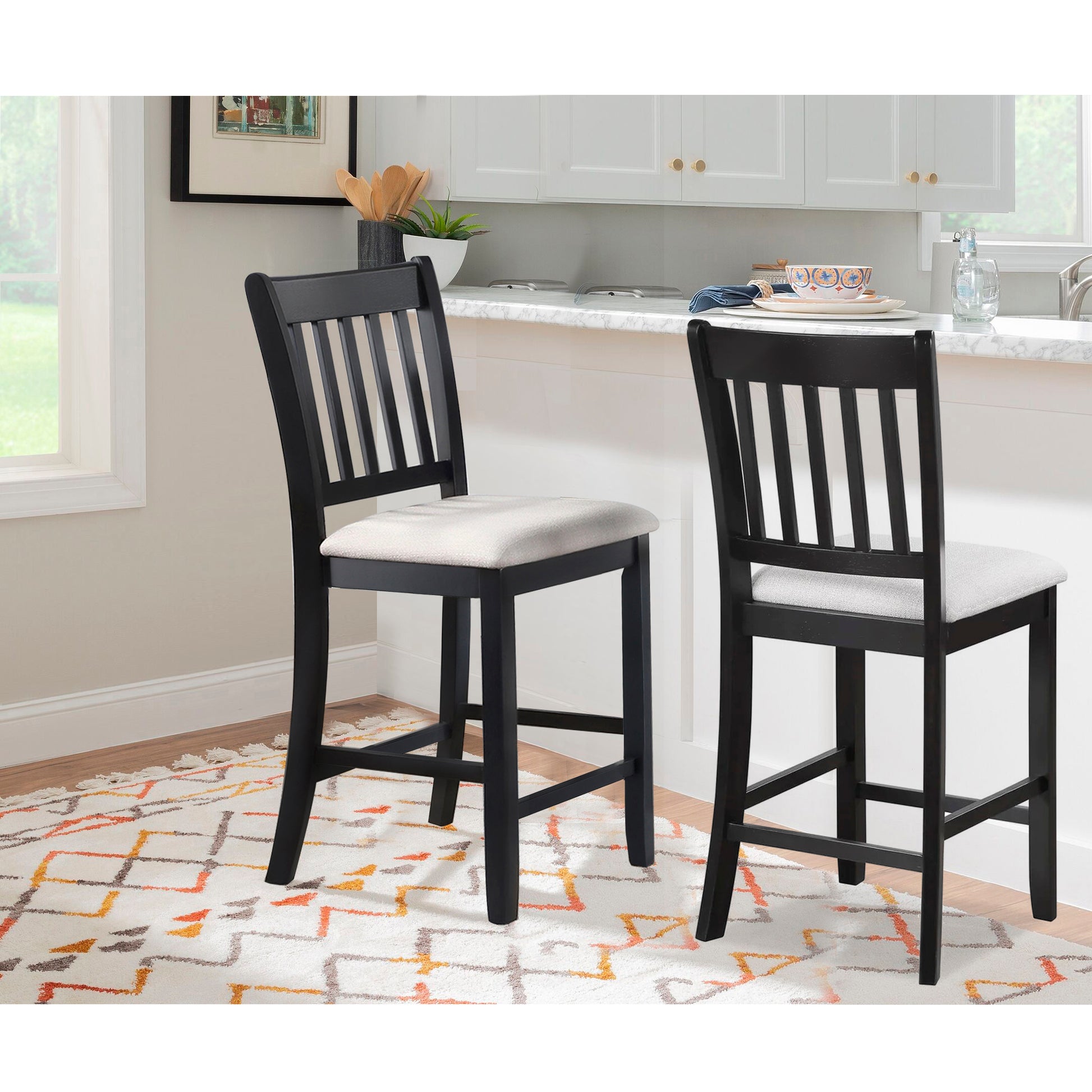 Two black wooden bar stools with light grey upholstered seats in a modern kitchen setting