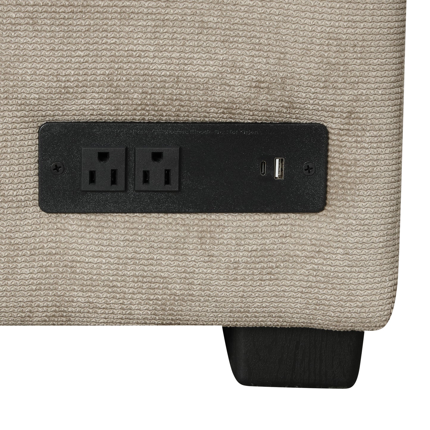 Closeup of a beige textured sofa arm with a black power outlet and dual USB charging ports