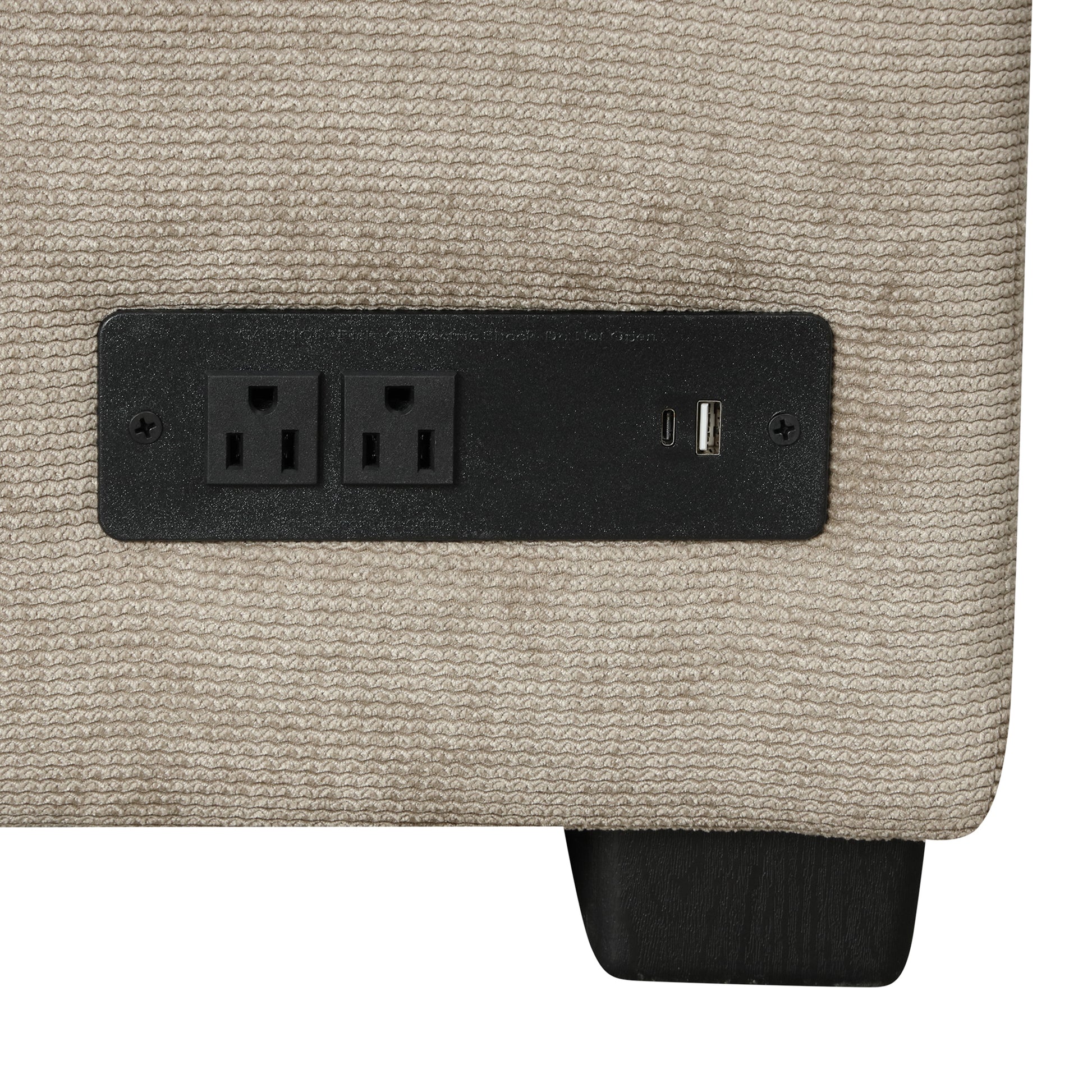 Closeup of a beige textured sofa arm with a black power outlet and dual USB charging ports