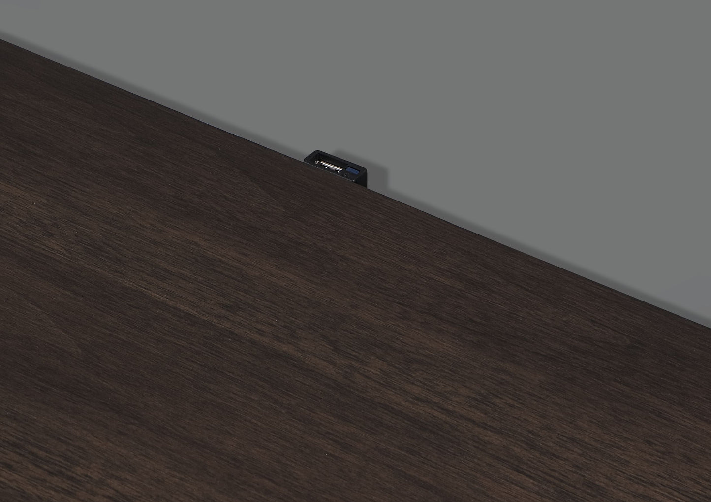 Dark wood desk surface with integrated USB charging port for convenient device power