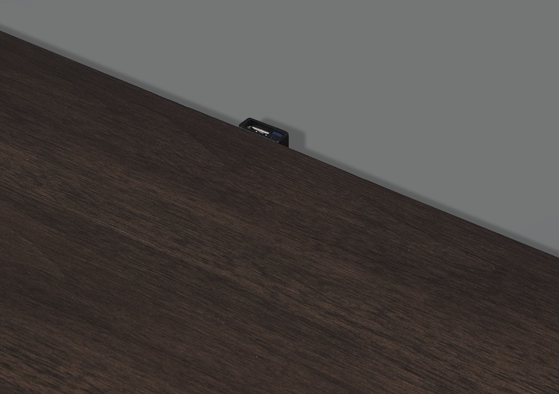 Dark wood desk surface with integrated USB charging port for convenient device power