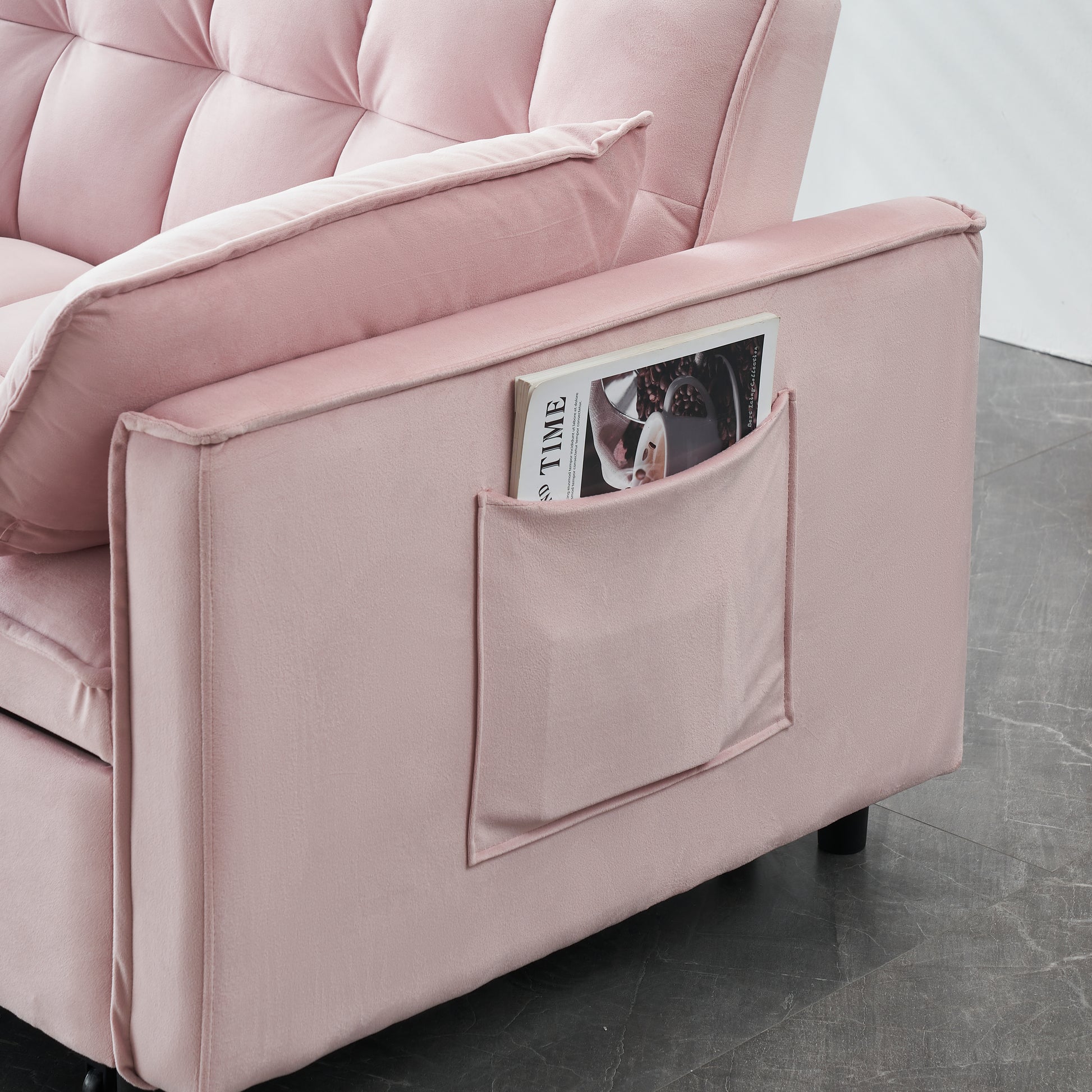 Plush pink velvet sofa with tufted cushions and convenient side pocket holding a magazine