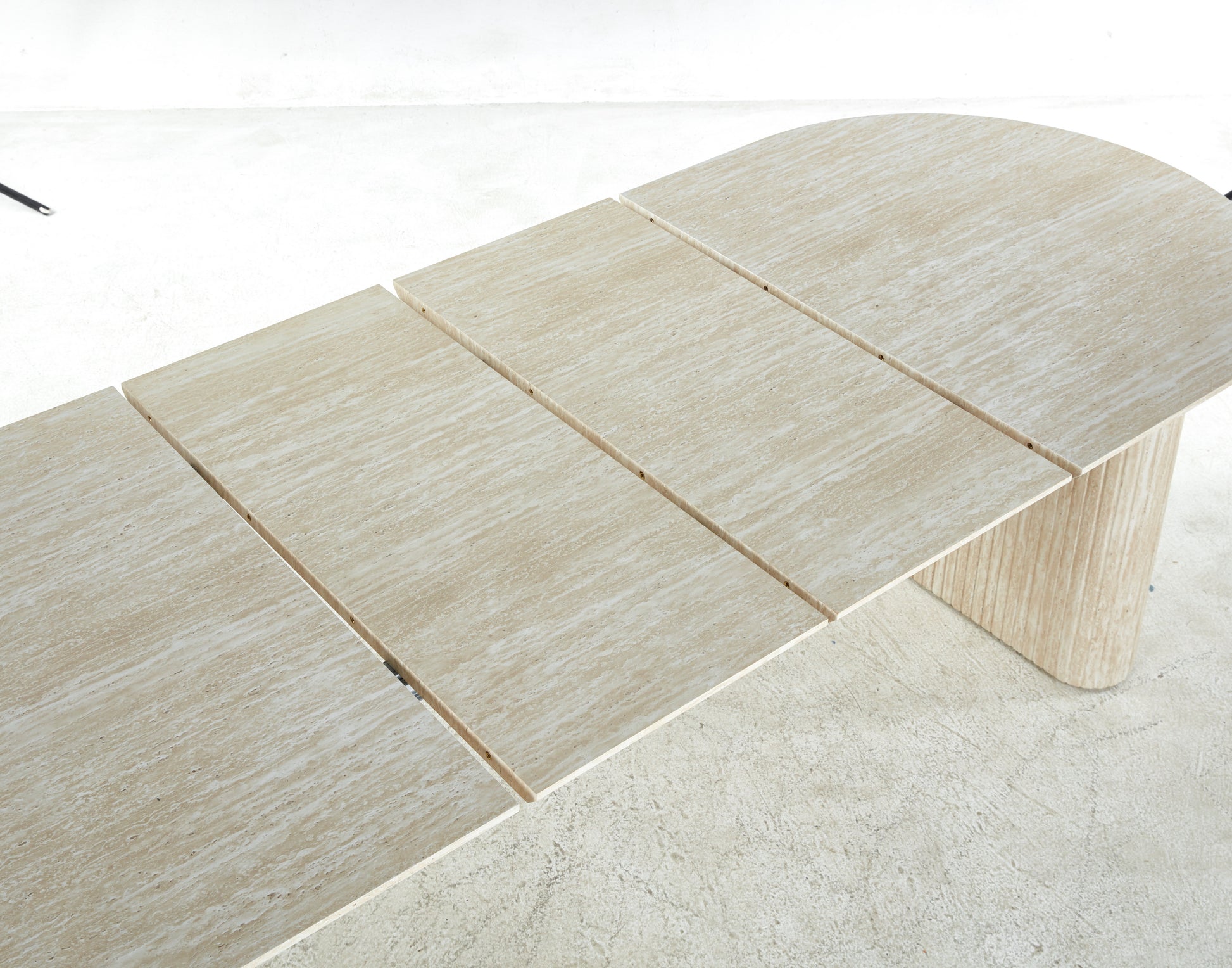 Extendable travertine dining table with natural stone texture and a rounded end