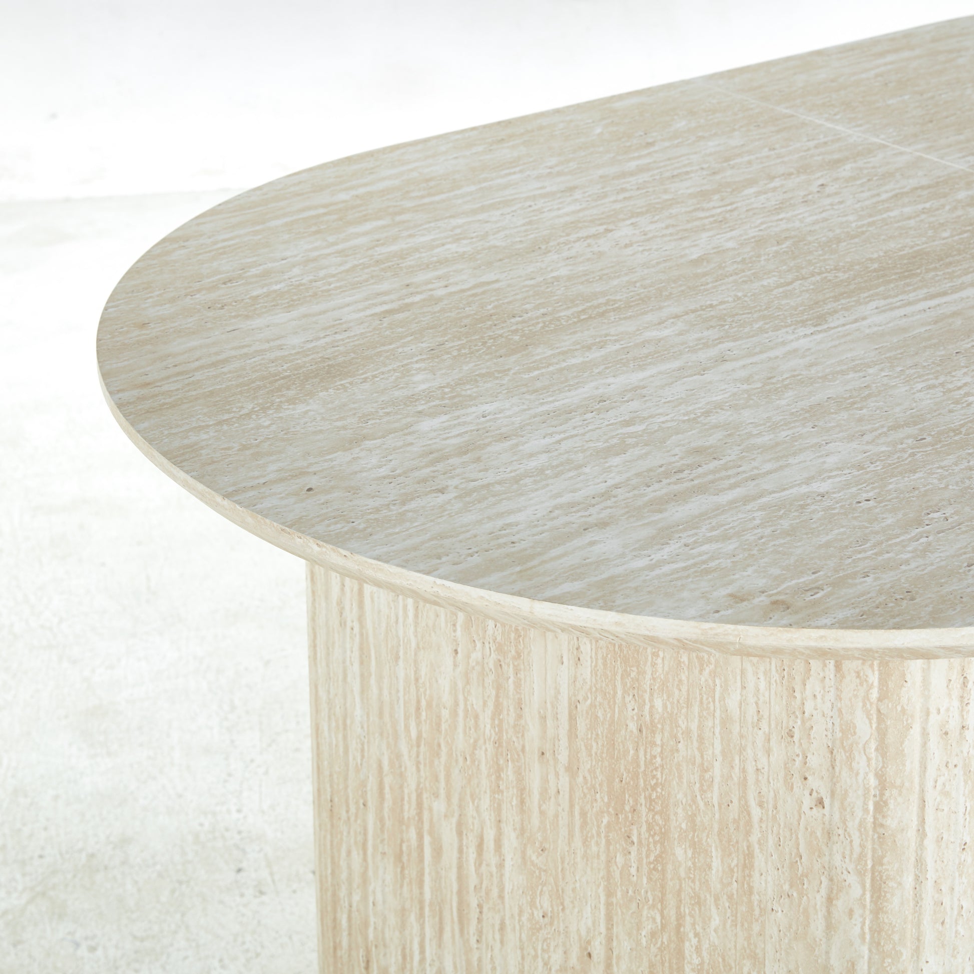 Oval travertine dining table with natural veining and a brushed finish