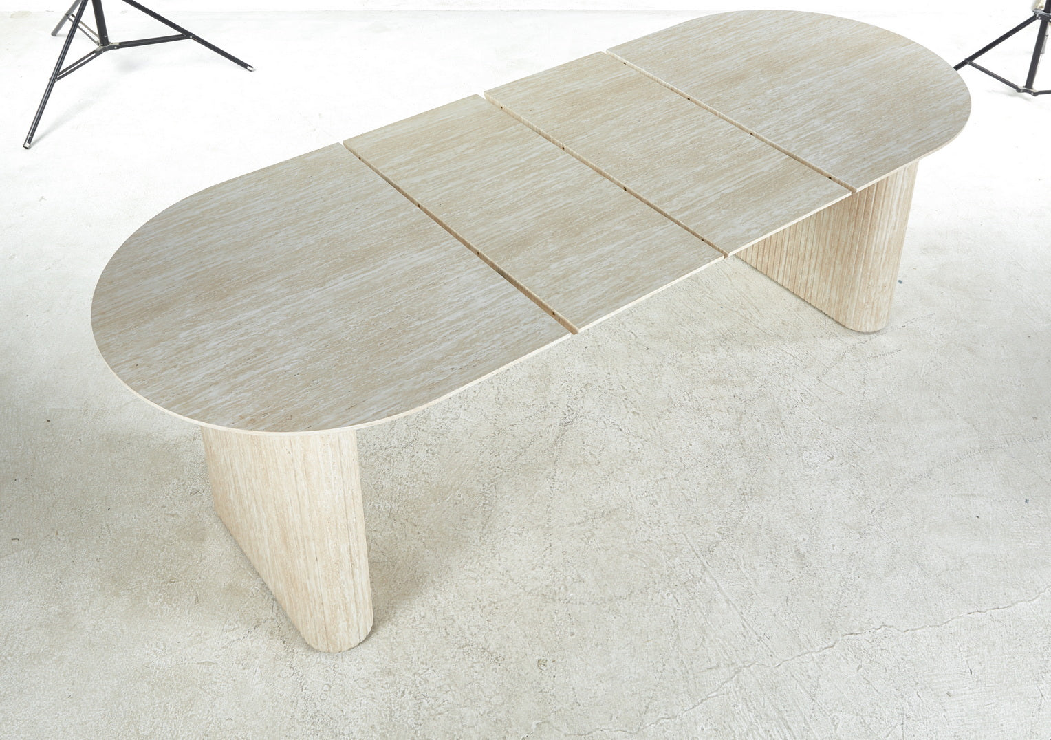 Light beige travertine dining table with oval top and fluted pedestal legs