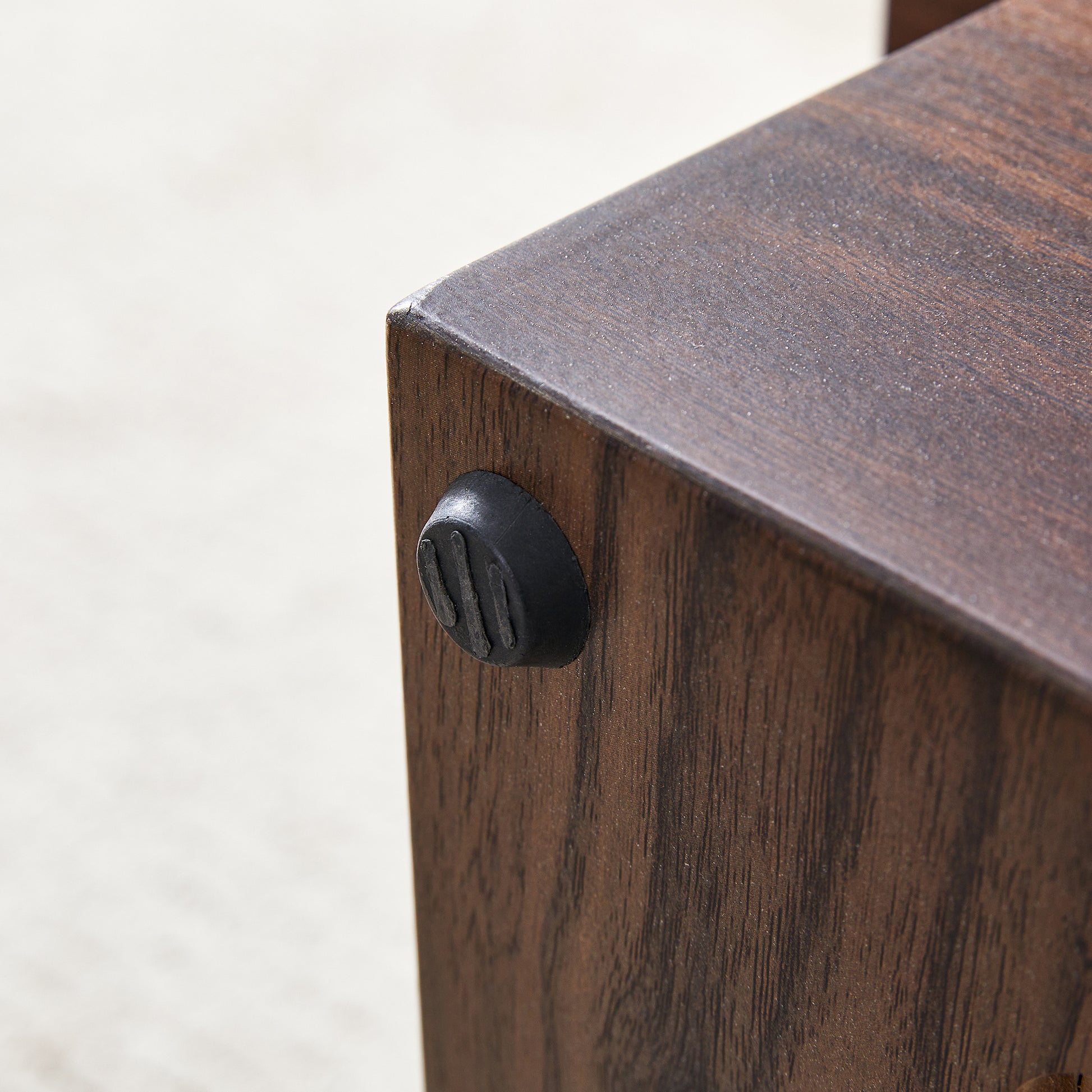 Dark wood grain texture on furniture leg with black antislip foot