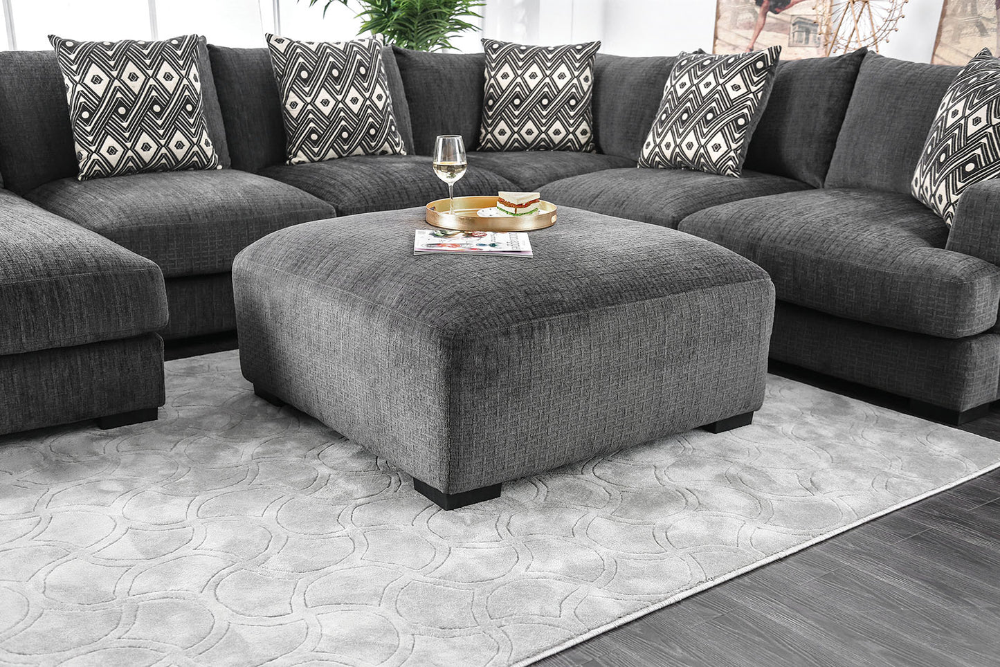 Dark gray fabric sectional sofa with patterned throw pillows and matching ottoman