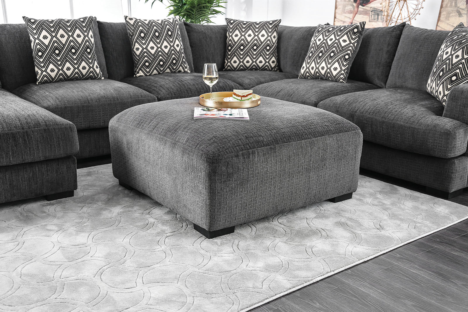 Dark gray fabric sectional sofa with patterned throw pillows and matching ottoman