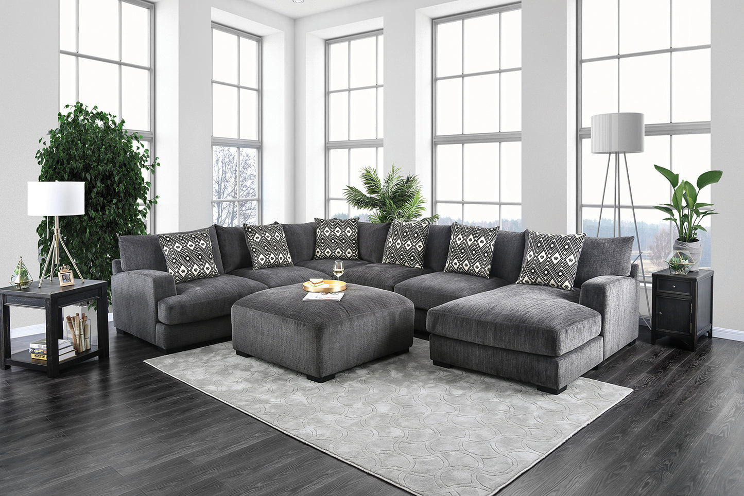 Spacious charcoal grey fabric sectional sofa with patterned accent pillows and matching ottoman
