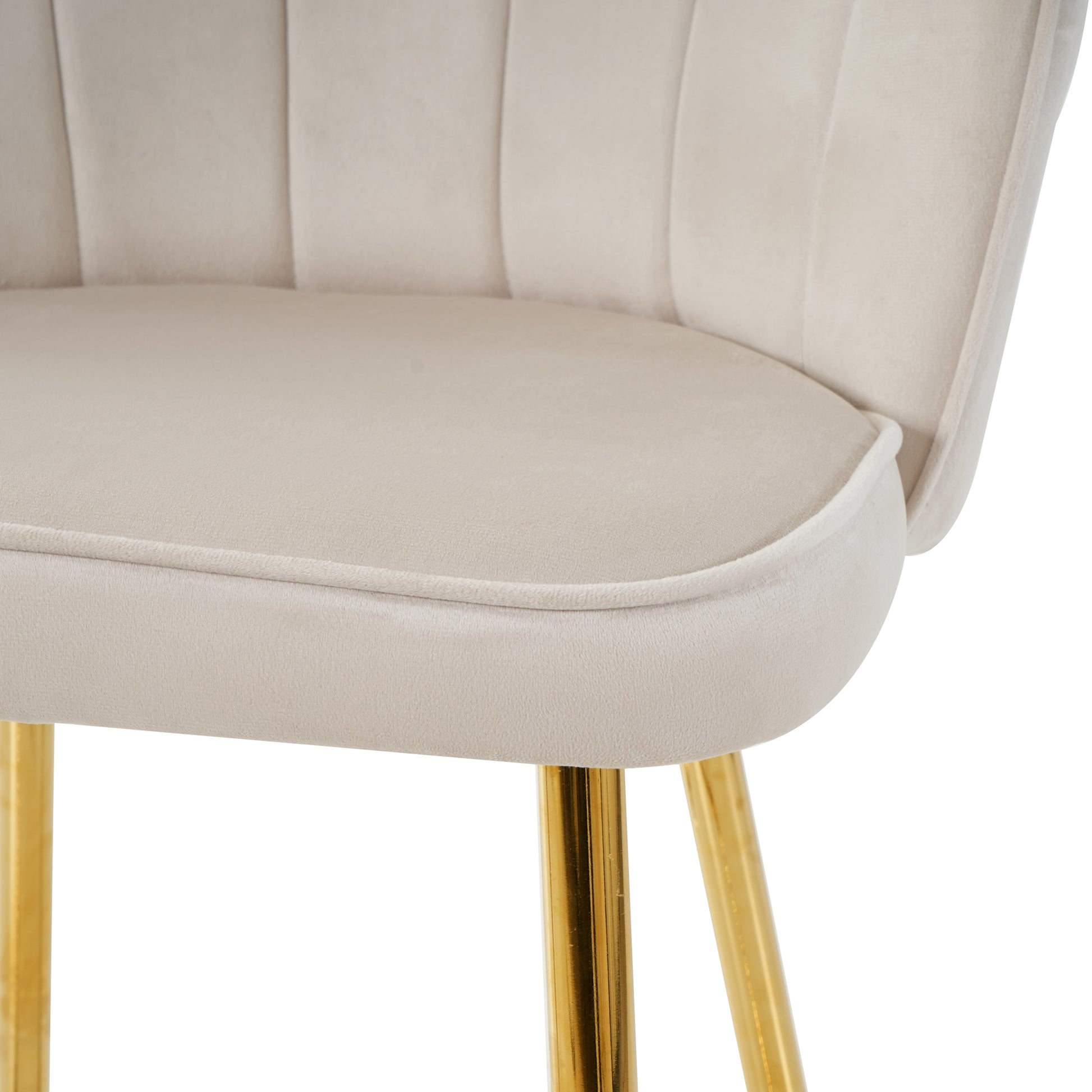 Closeup of a plush cream velvet accent chair with channel tufting and gold legs