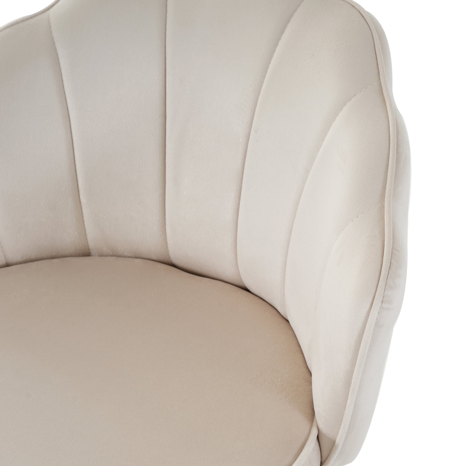 Closeup of a beige velvet armchair with scalloped backrest and piped edges