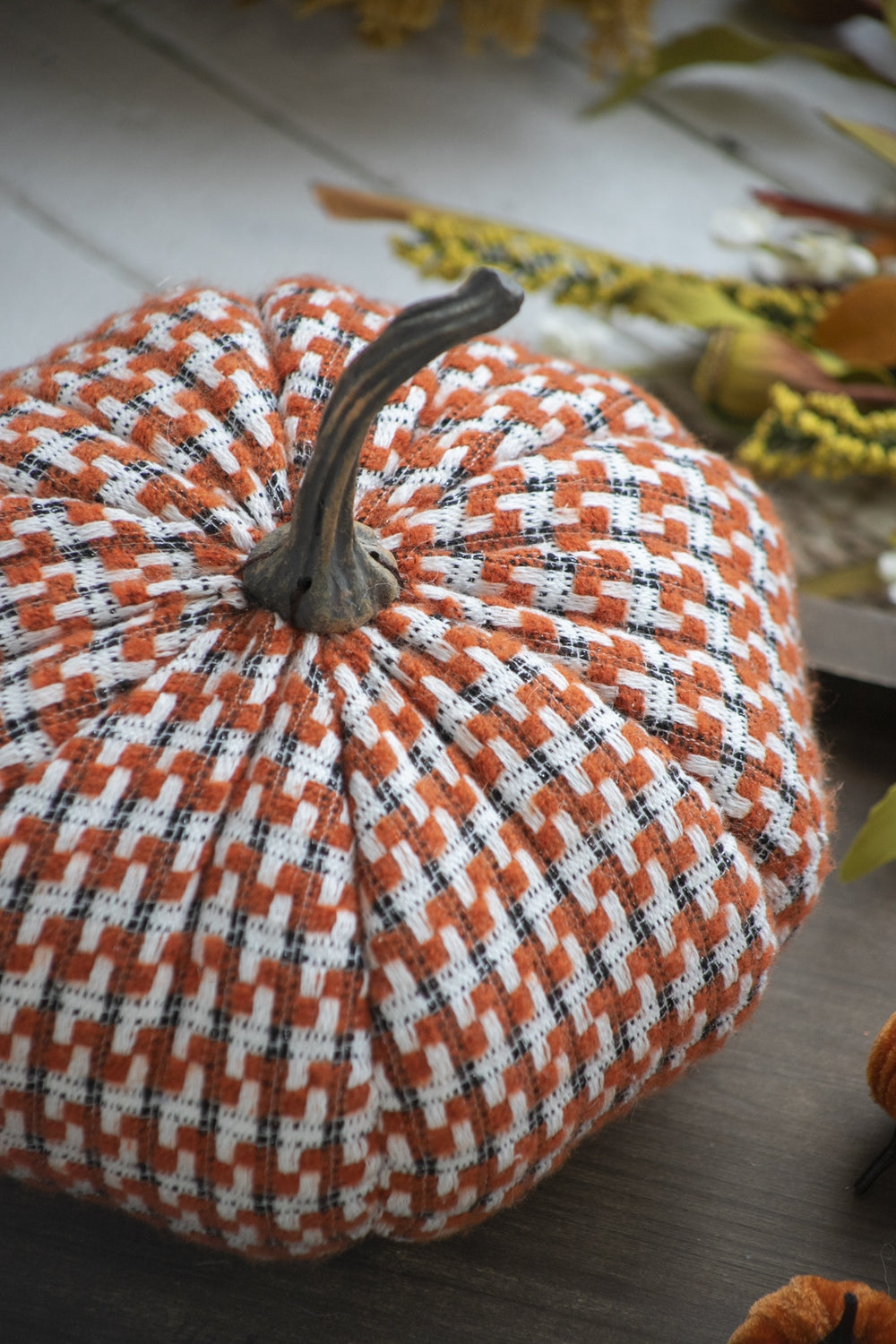 Fabric pumpkin decoration in orange white and black plaid with realistic stem