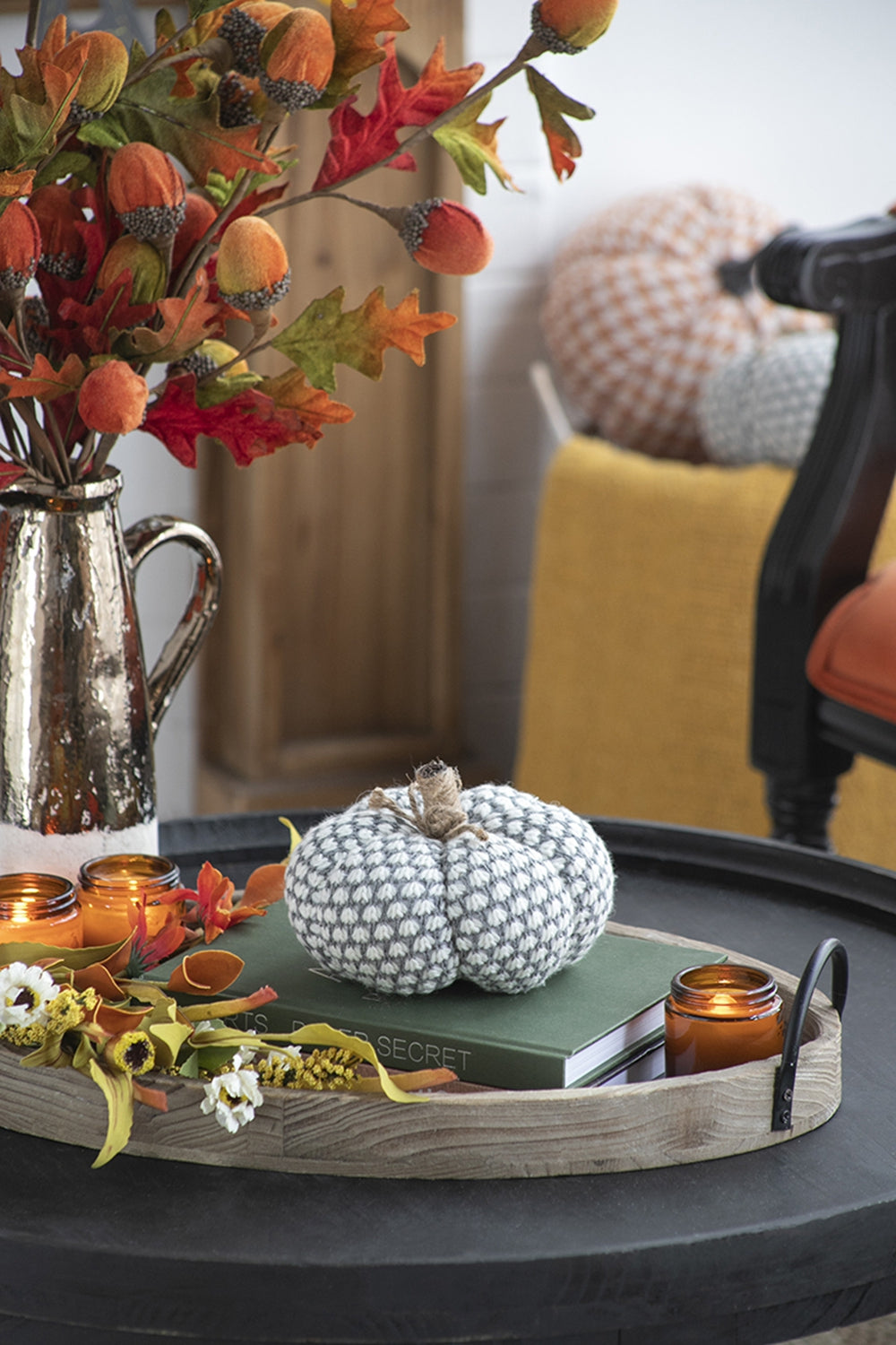 Grey and white knit pumpkin with twine stem on a green book