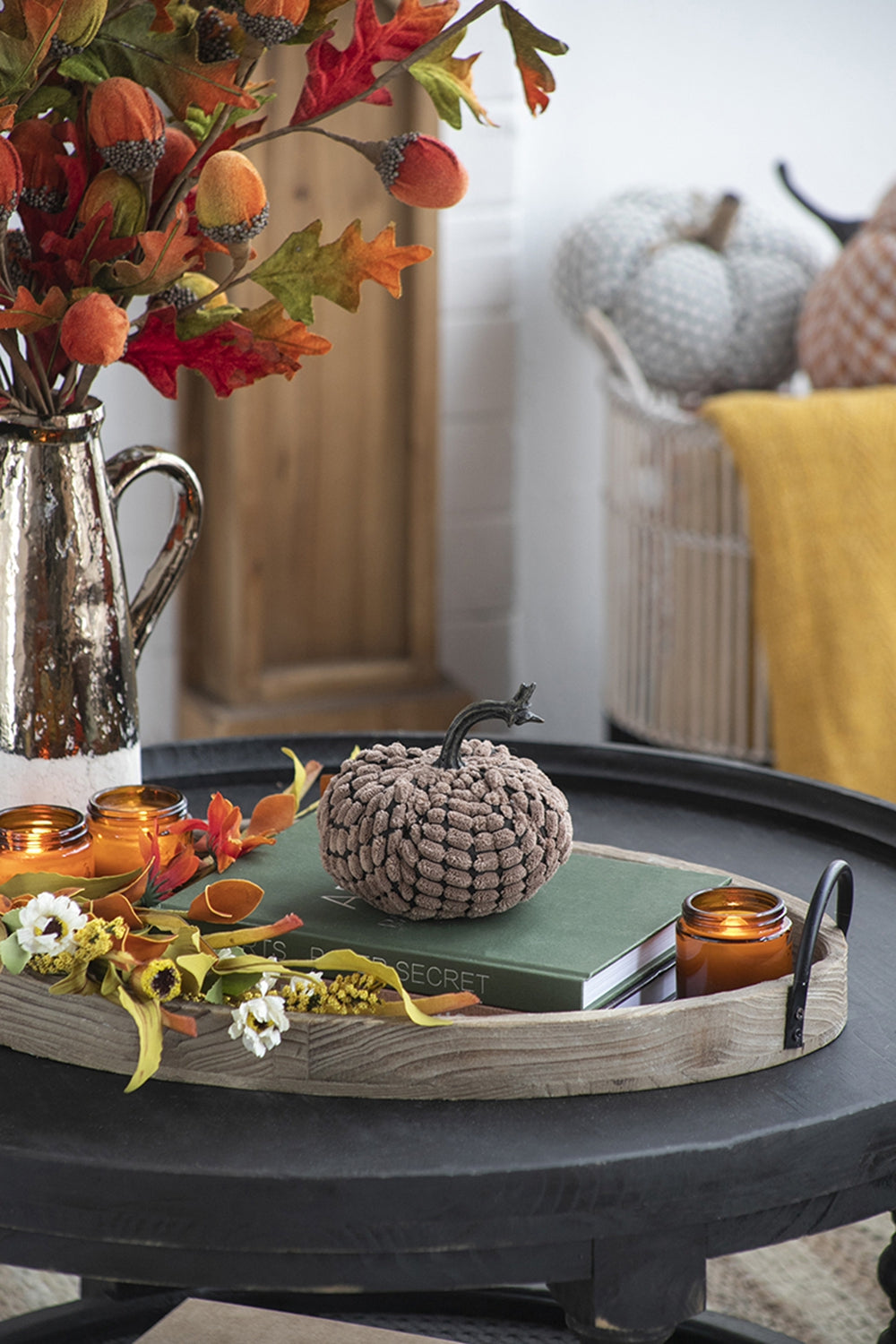 Brown knitted pumpkin with stem on green book autumn decor accent