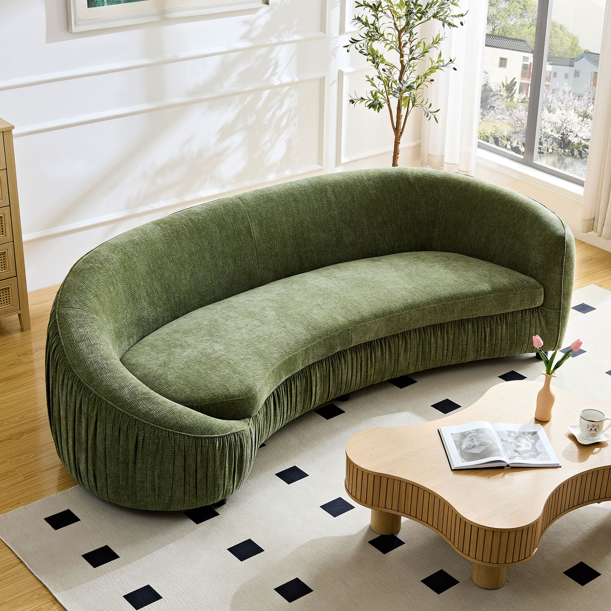 Curved green velvet sofa with pleated skirt detail perfect for living room seating