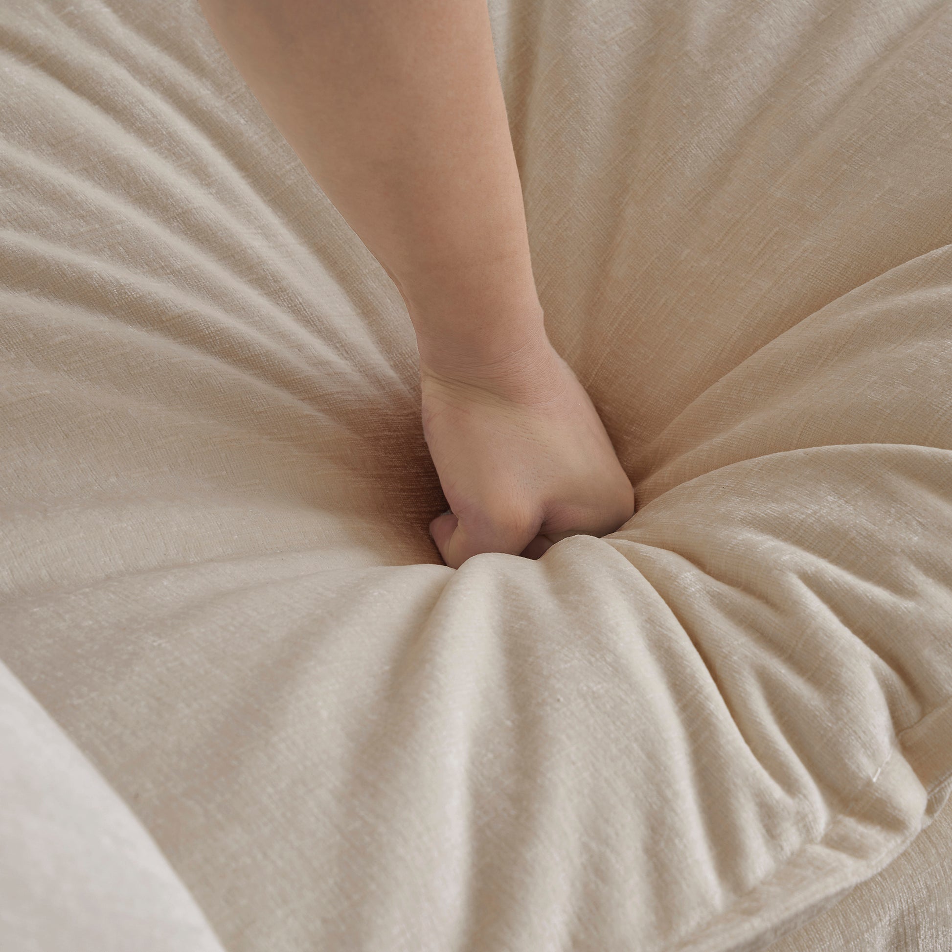 Hand pressing into plush beige linen fabric showcasing its softness for home decor